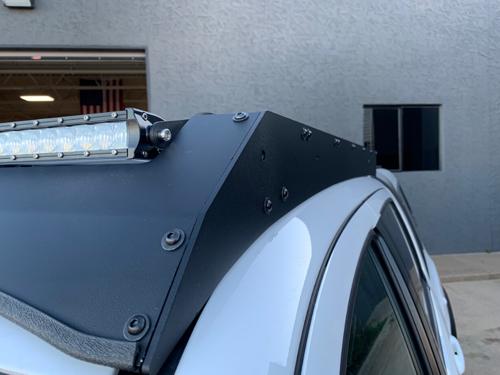 Close-up of off-road roof rack with LED light bar mounted on a white vehicle