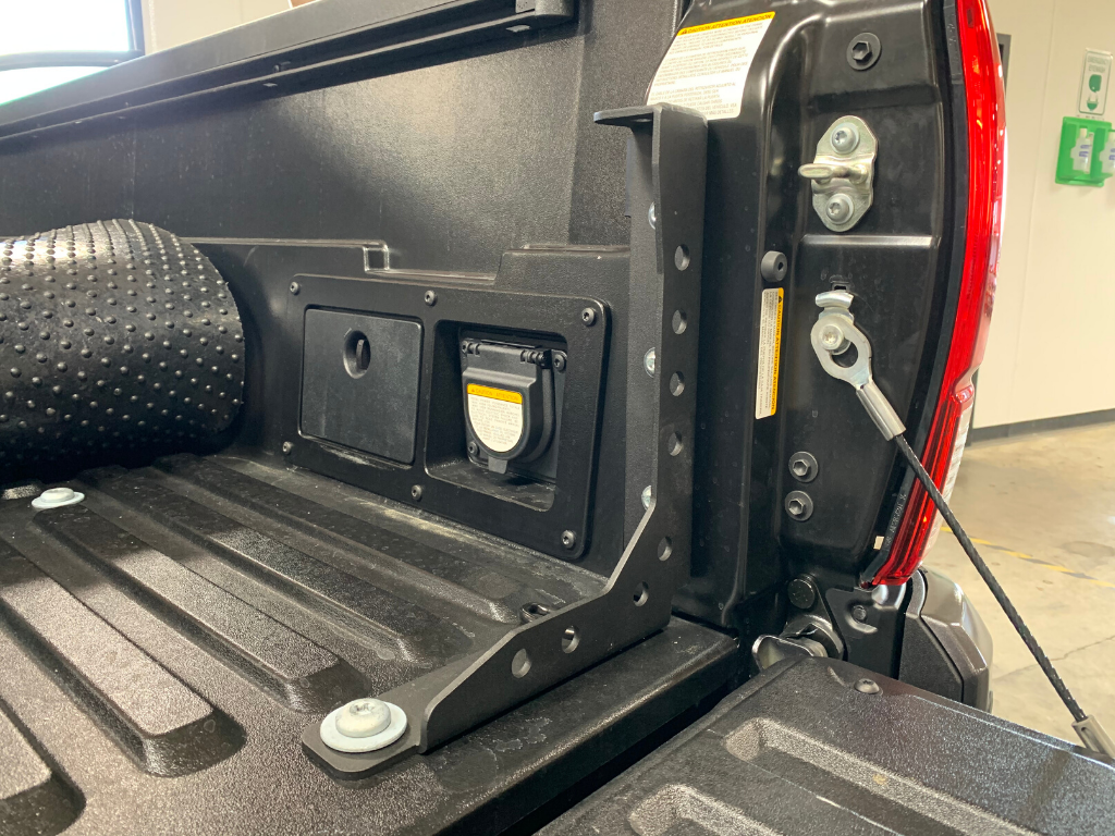 Close-up of a truck bed rack mounting bracket installed on a pickup tailgate