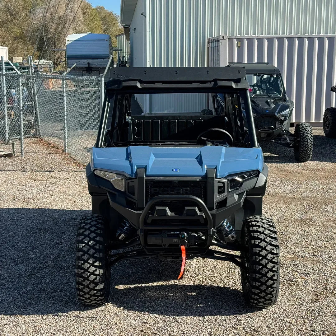 Blue off-road adventure vehicle with rugged tires and winch parked on gravel lot