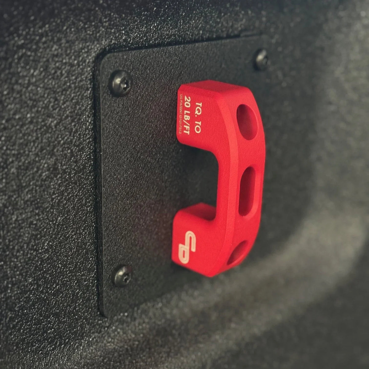 Red powder-coated tie down point mounted on textured truck bed panel