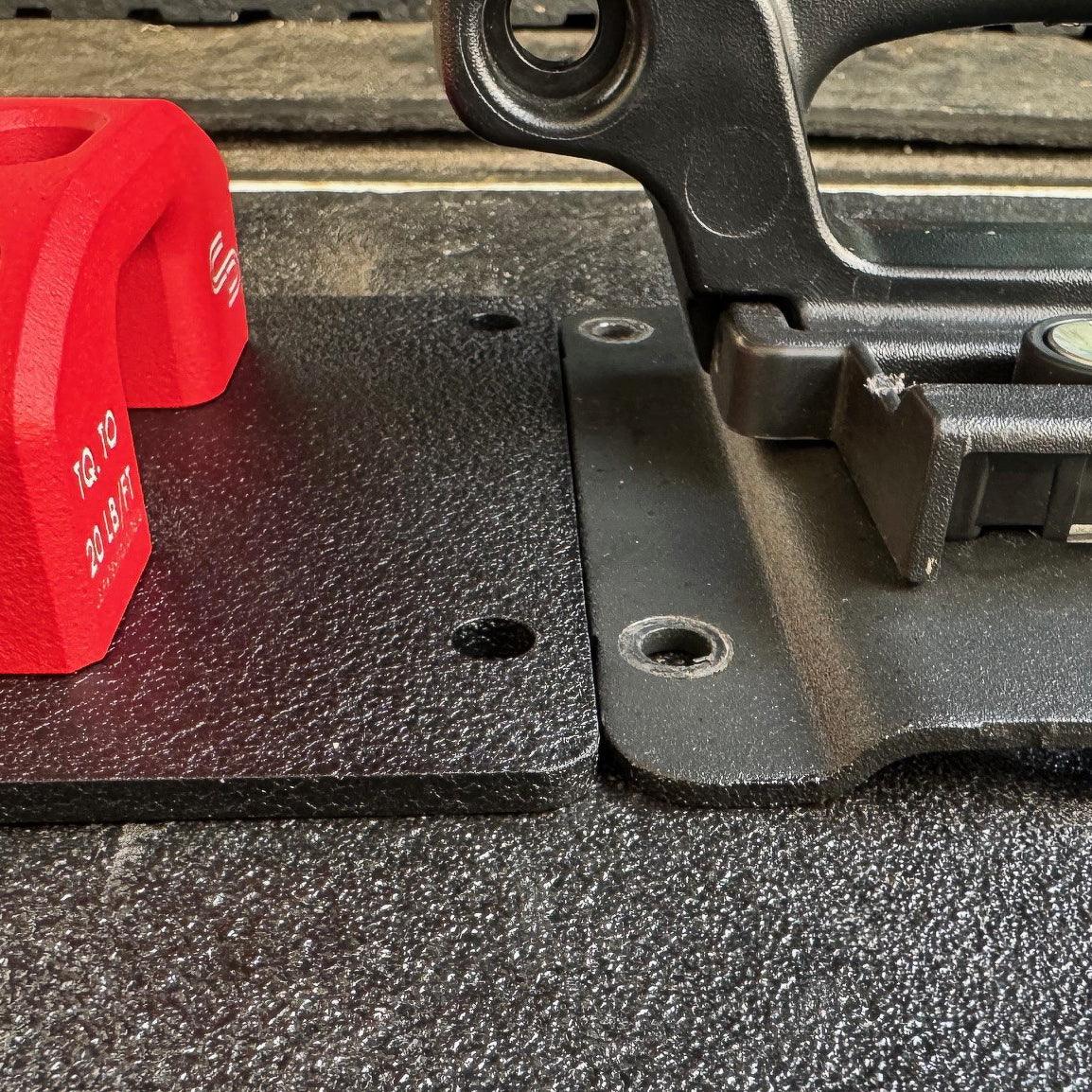 Black metal replacement mounting plate with red accessory for overlanding vehicle