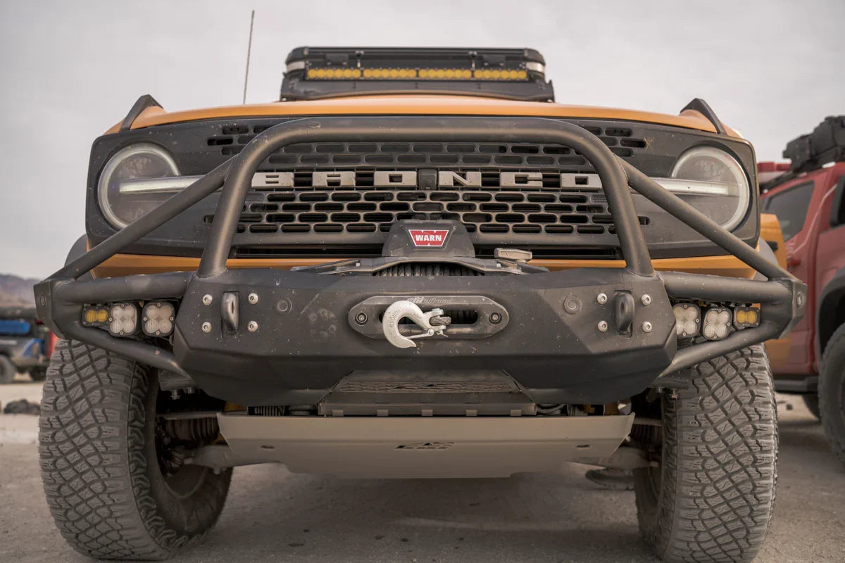 Ford Bronco with off-road front bumper, winch, and camping gear in outdoor setting
