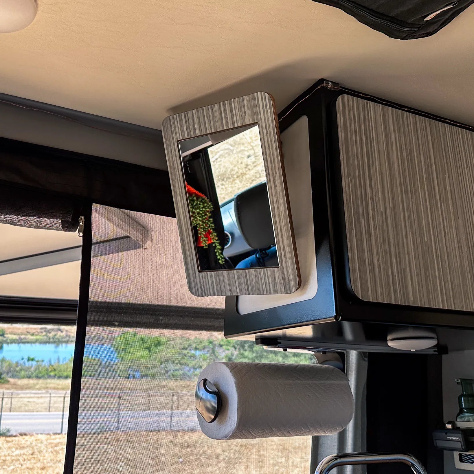 Rectangular track-mounted mirror and paper towel holder in an overland camper van interior