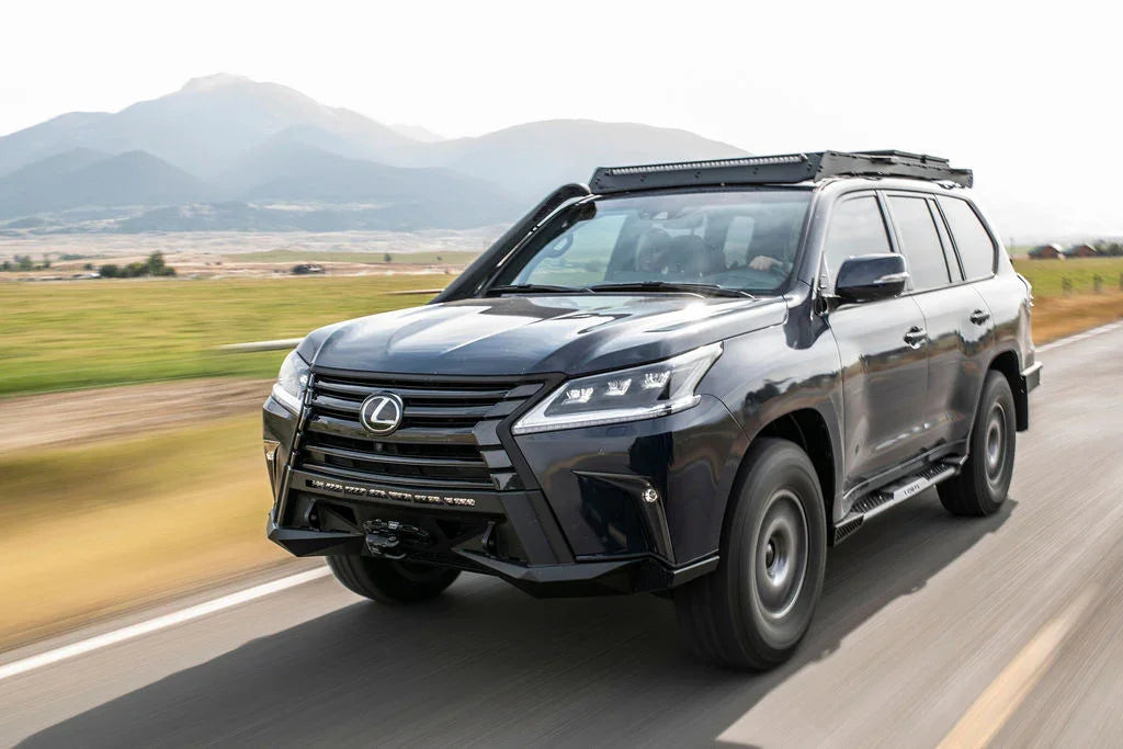 Lexus LX570 SUV with covert front bumper driving on open road, mountains in background