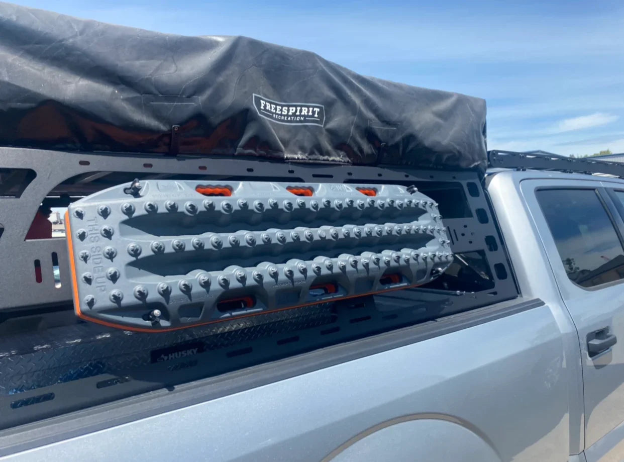 Ford F-150 with cab height bed rack, recovery boards, and rooftop tent for overlanding