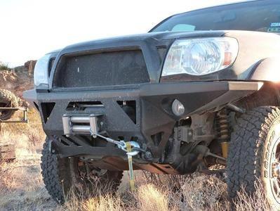 Toyota Tacoma with off-road steel front bumper and winch in rugged outdoor terrain