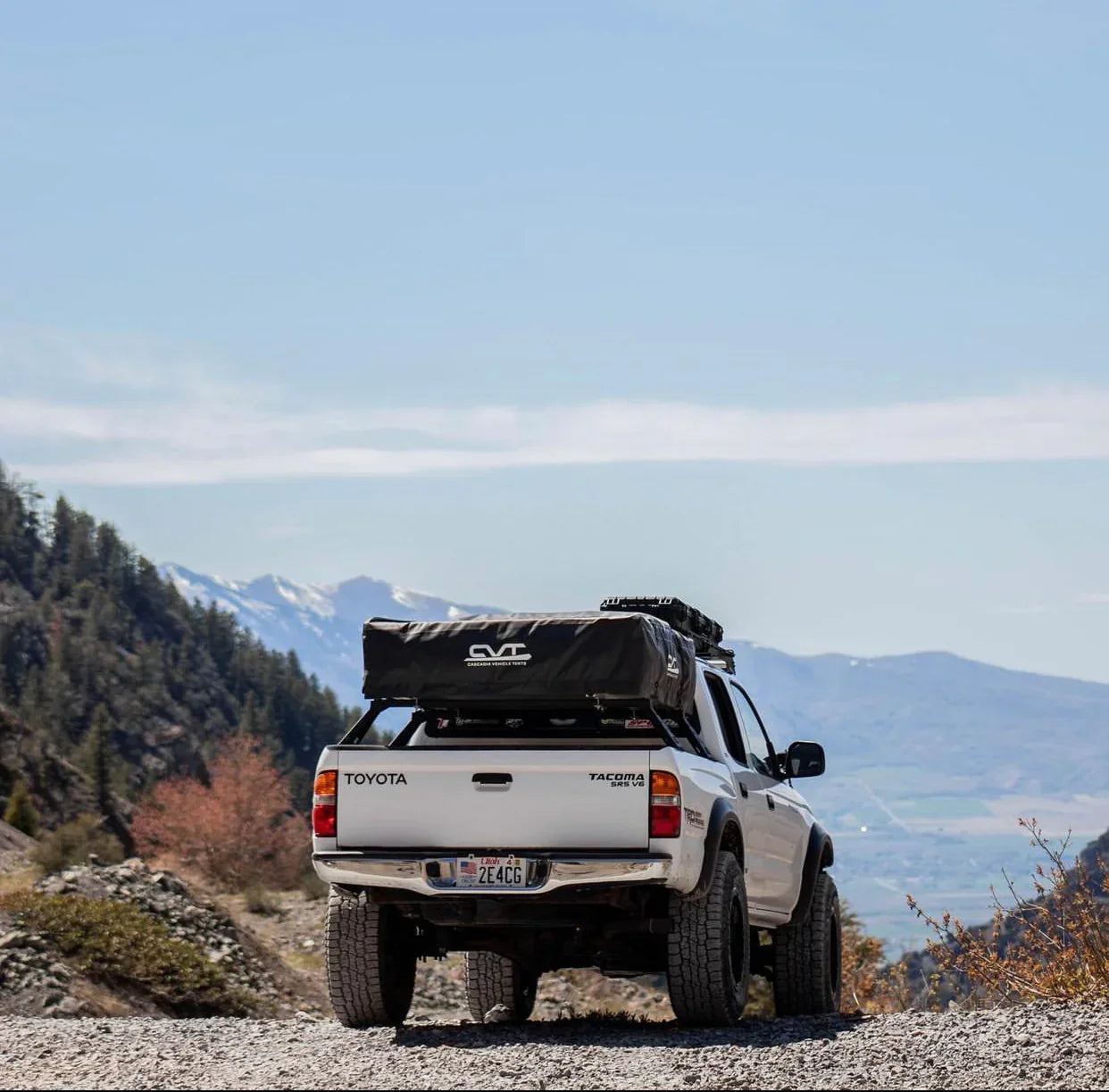 Toyota Tacoma with overland bed bars and roof tent parked on mountain trail