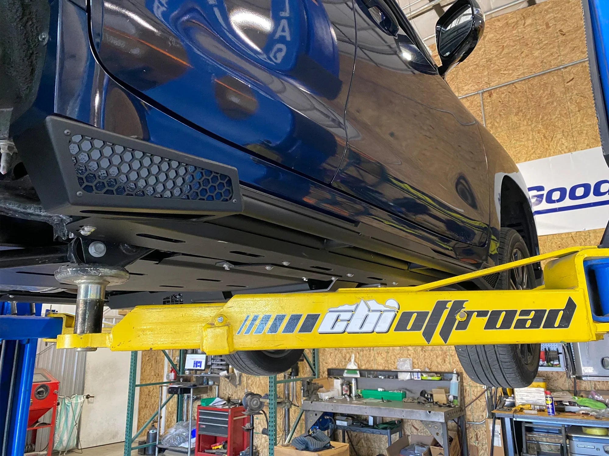 Lexus LX570 with CBI offroad rock sliders installed on a lift in a workshop