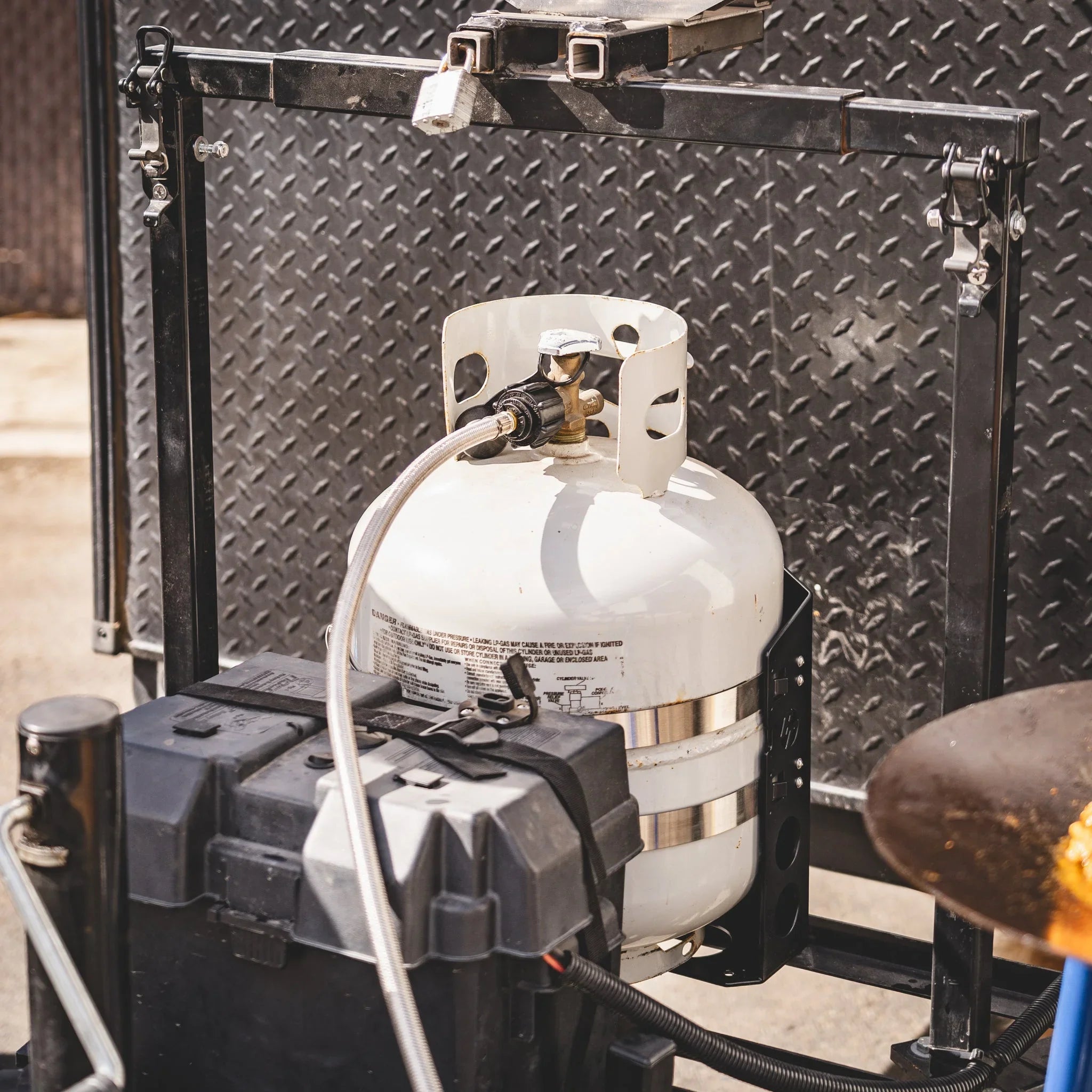 Propane tank mounted on a vehicle with hose connection for overlanding or camping use