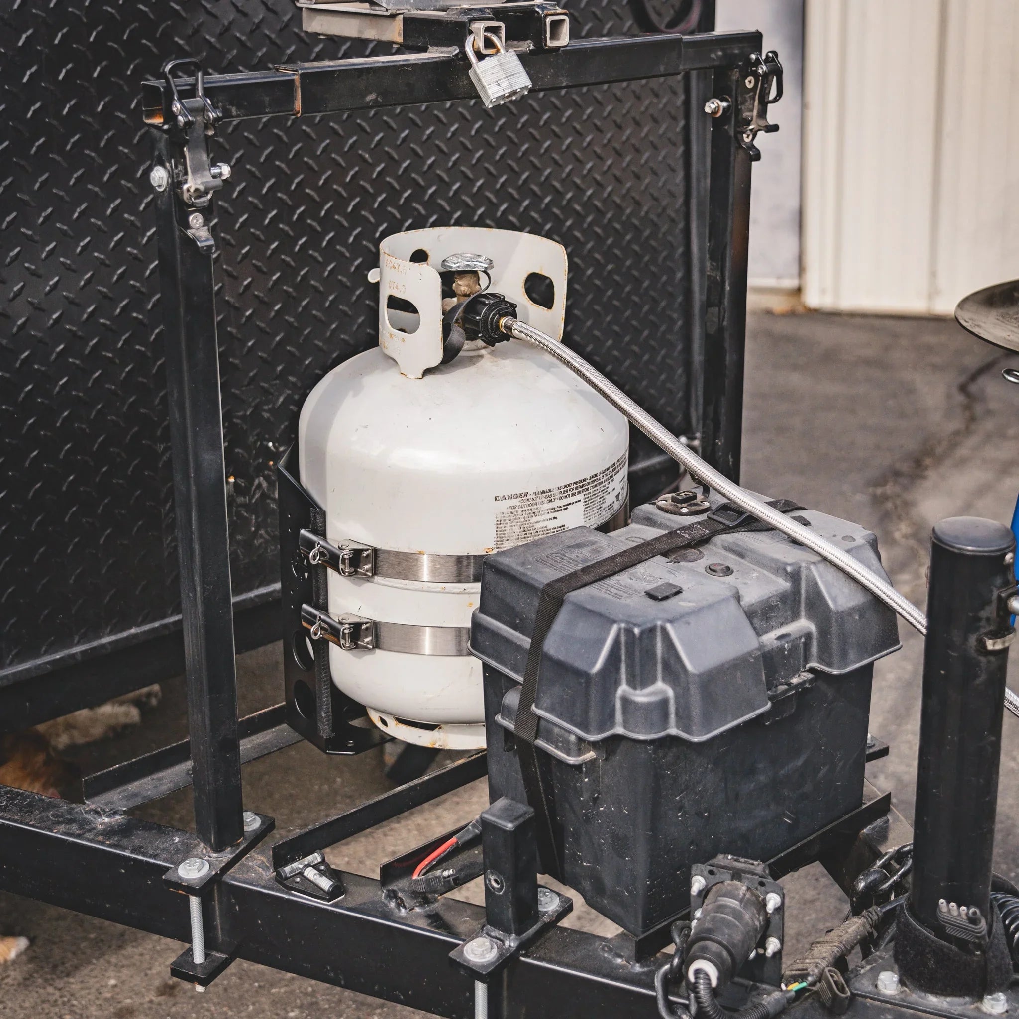 Propane tank mounted on trailer hitch with battery box, overlanding gear setup