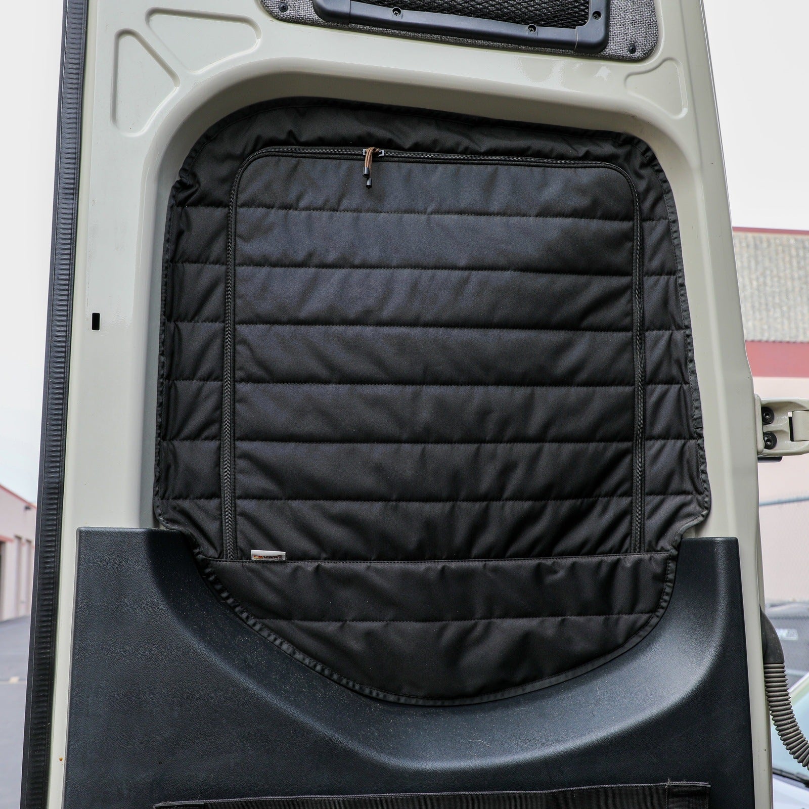 Quilted black insulated van door cover mounted inside vehicle for overlanding and camping