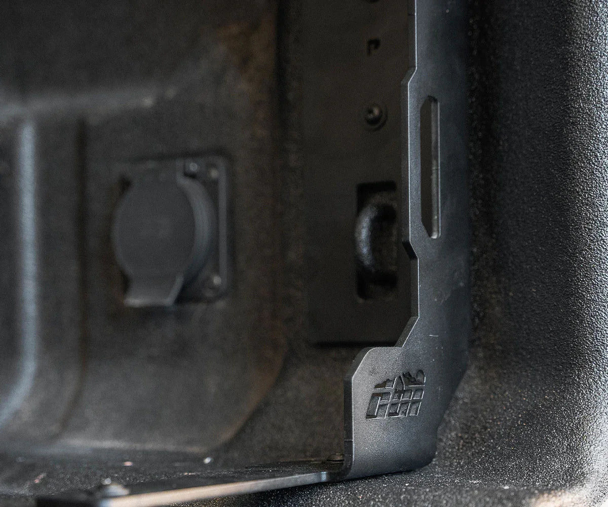 Steel bed stiffener bracket installed inside a truck bed, close-up view, overlanding gear