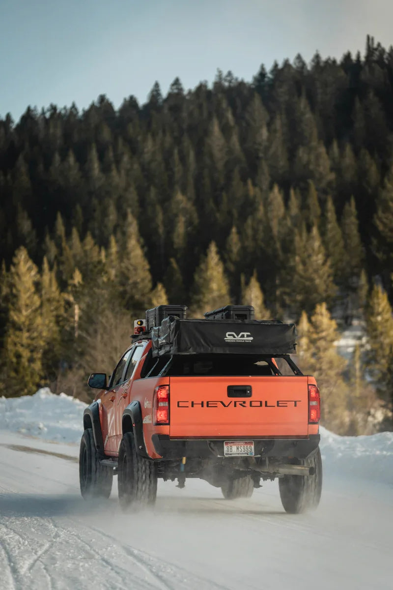 Chevrolet Colorado ZR2 with overlanding rear bumper and gear driving on snowy road in forest