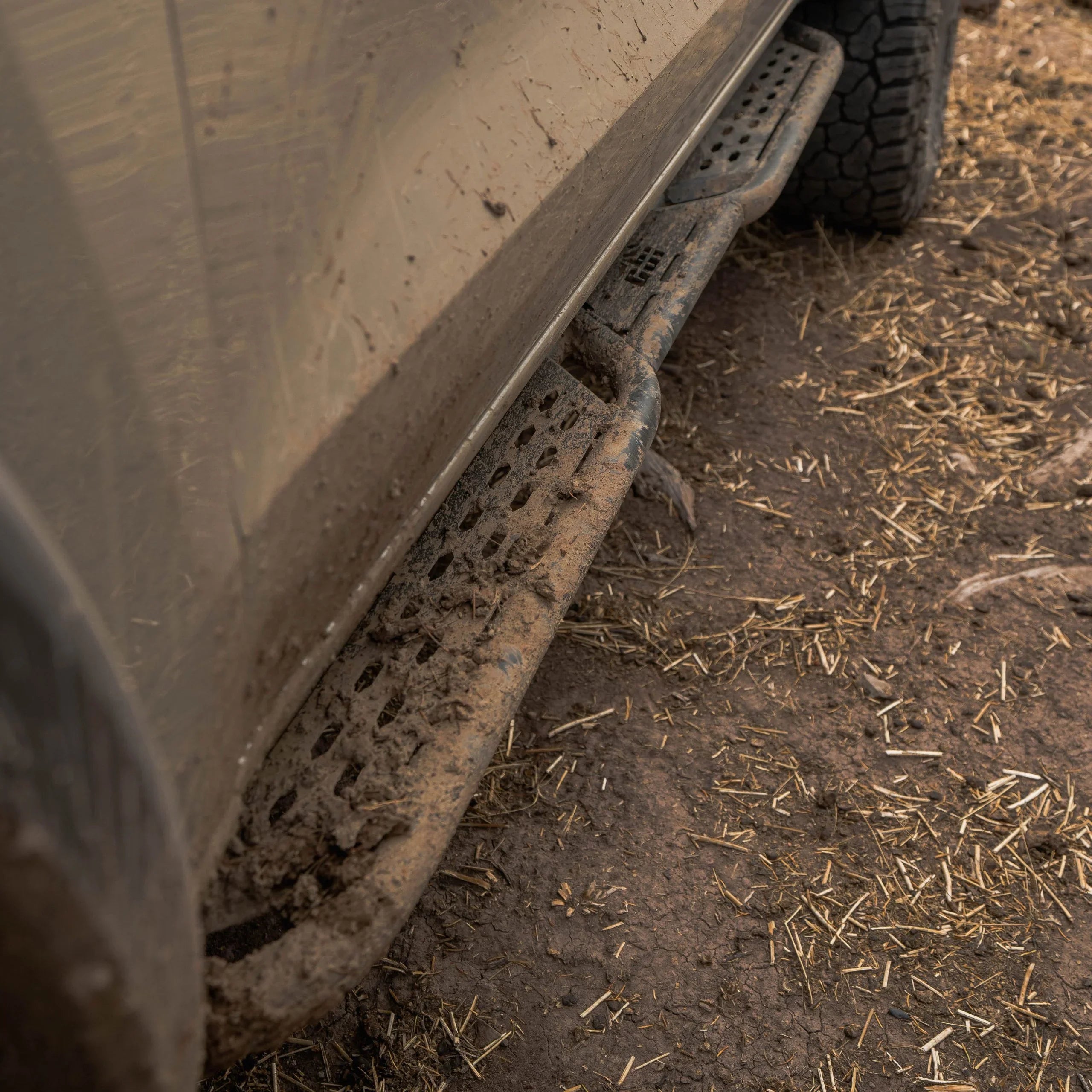 Muddy off-road vehicle with rugged side step rock slider in dirt terrain