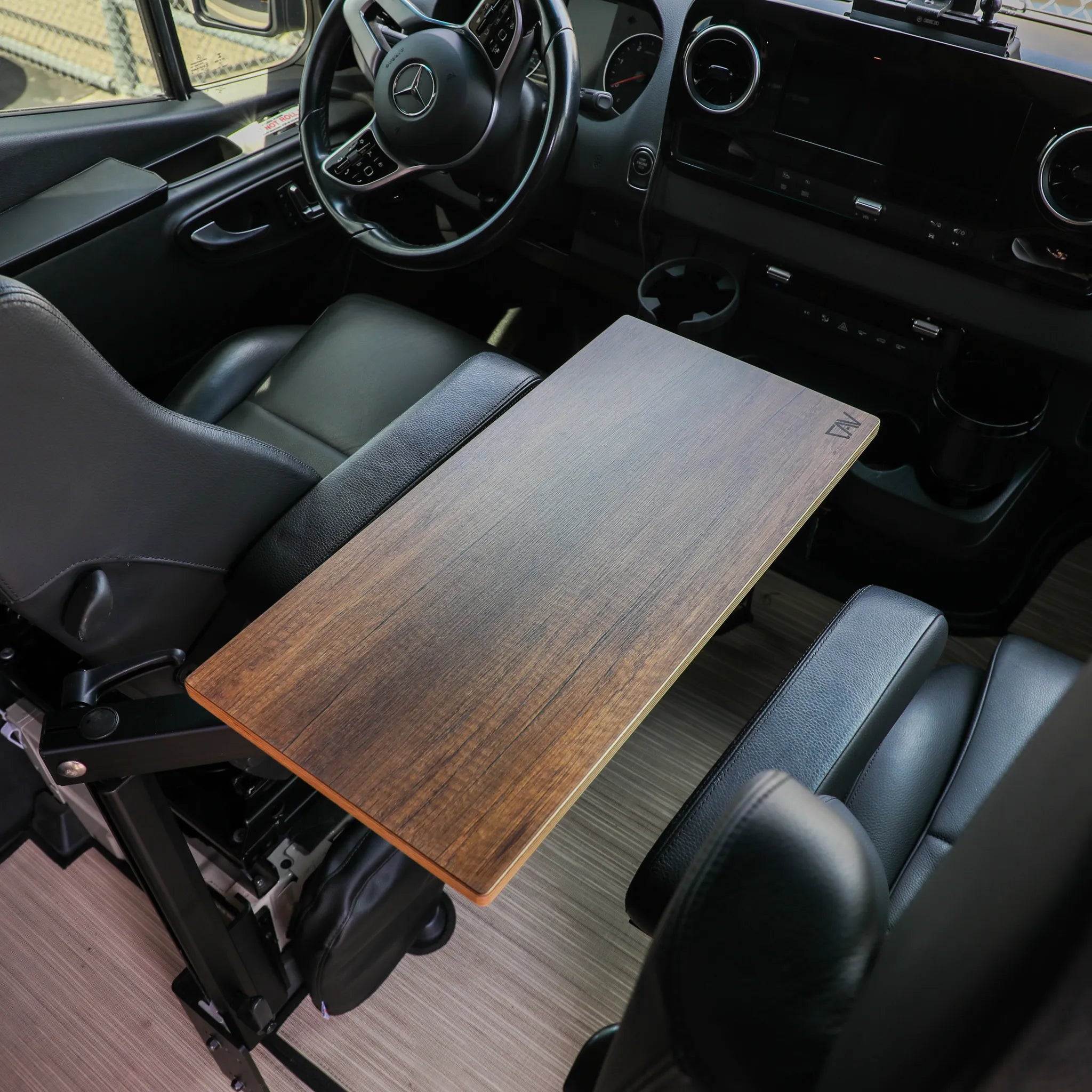 Overland vehicle interior with wood center console table and black leather seats