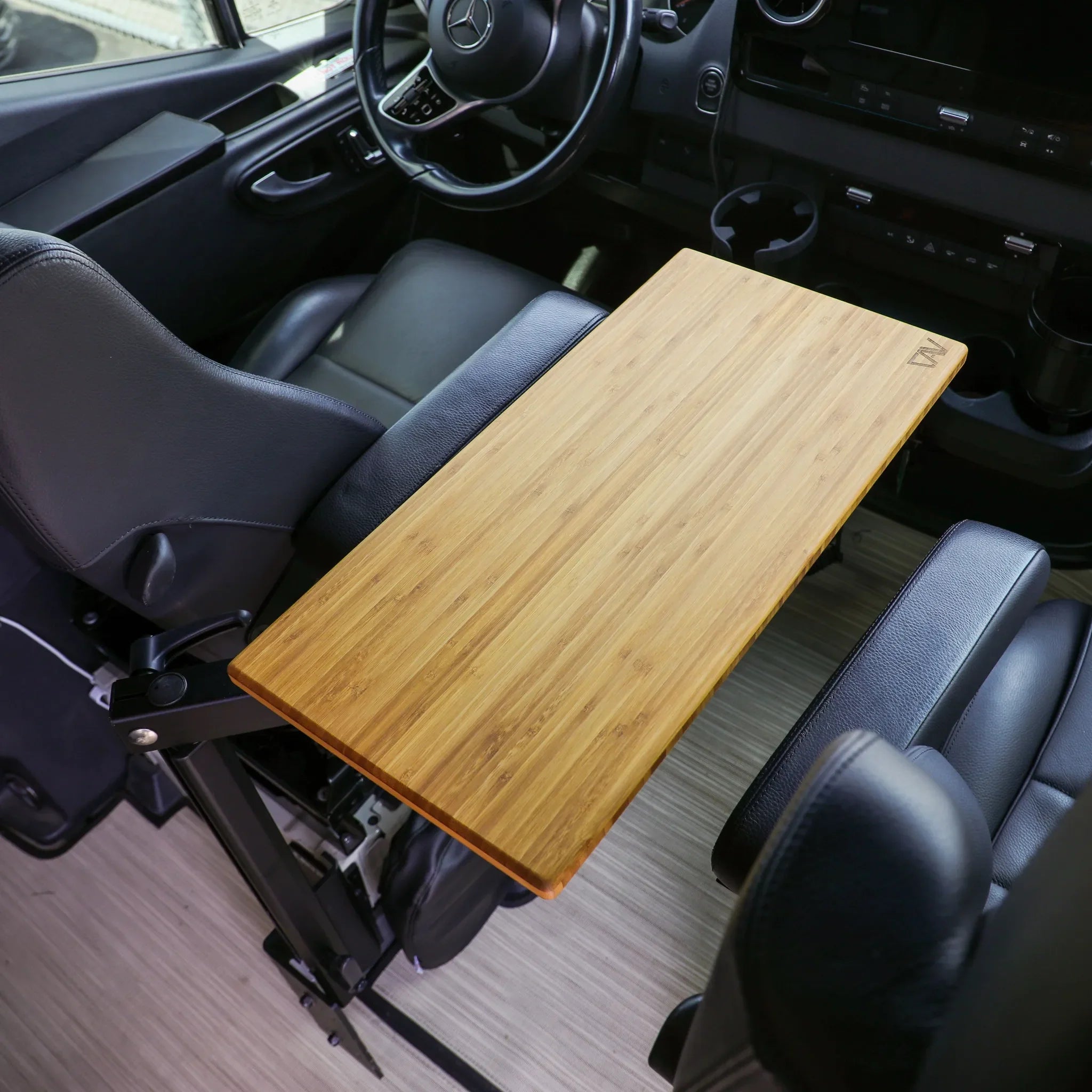 Bamboo vehicle console table mounted between black leather seats in a van interior