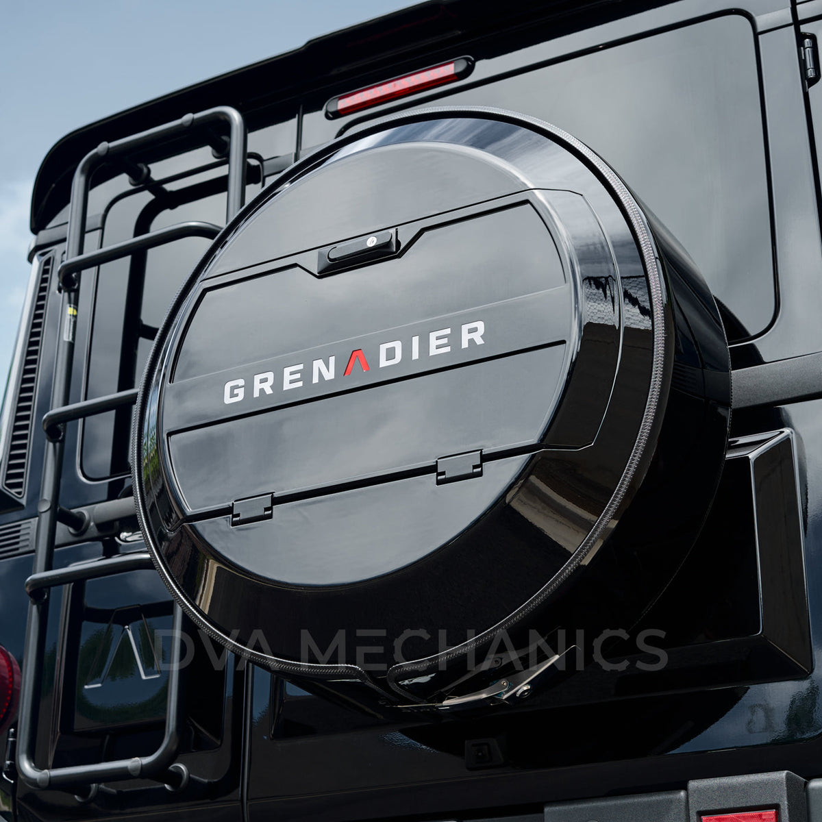 DVA Mechanics black spare tire utility cover with Grenadier lettering on the rear door of an INEOS Grenadier