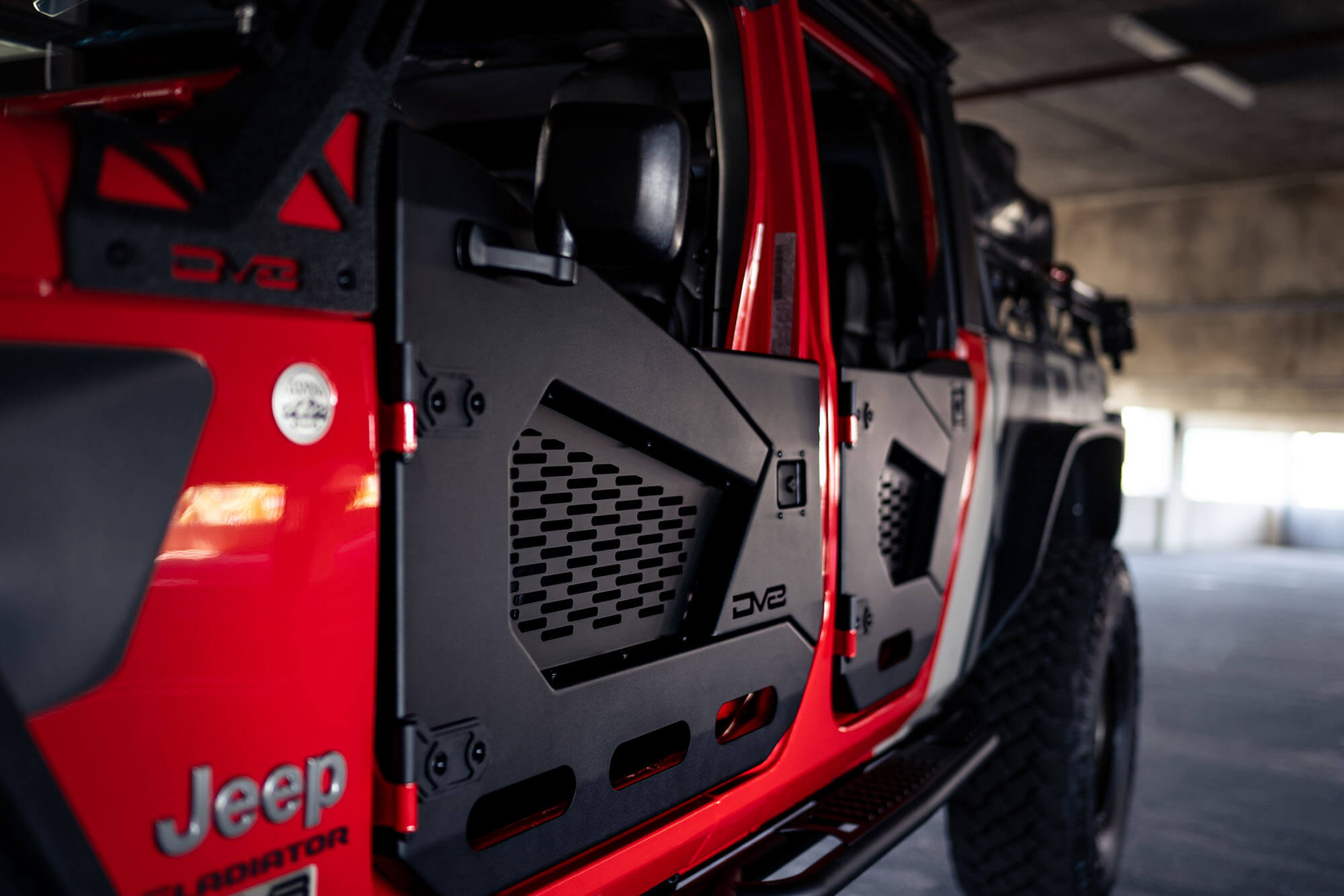 Red Jeep Gladiator with black off-road half doors in a parking garage