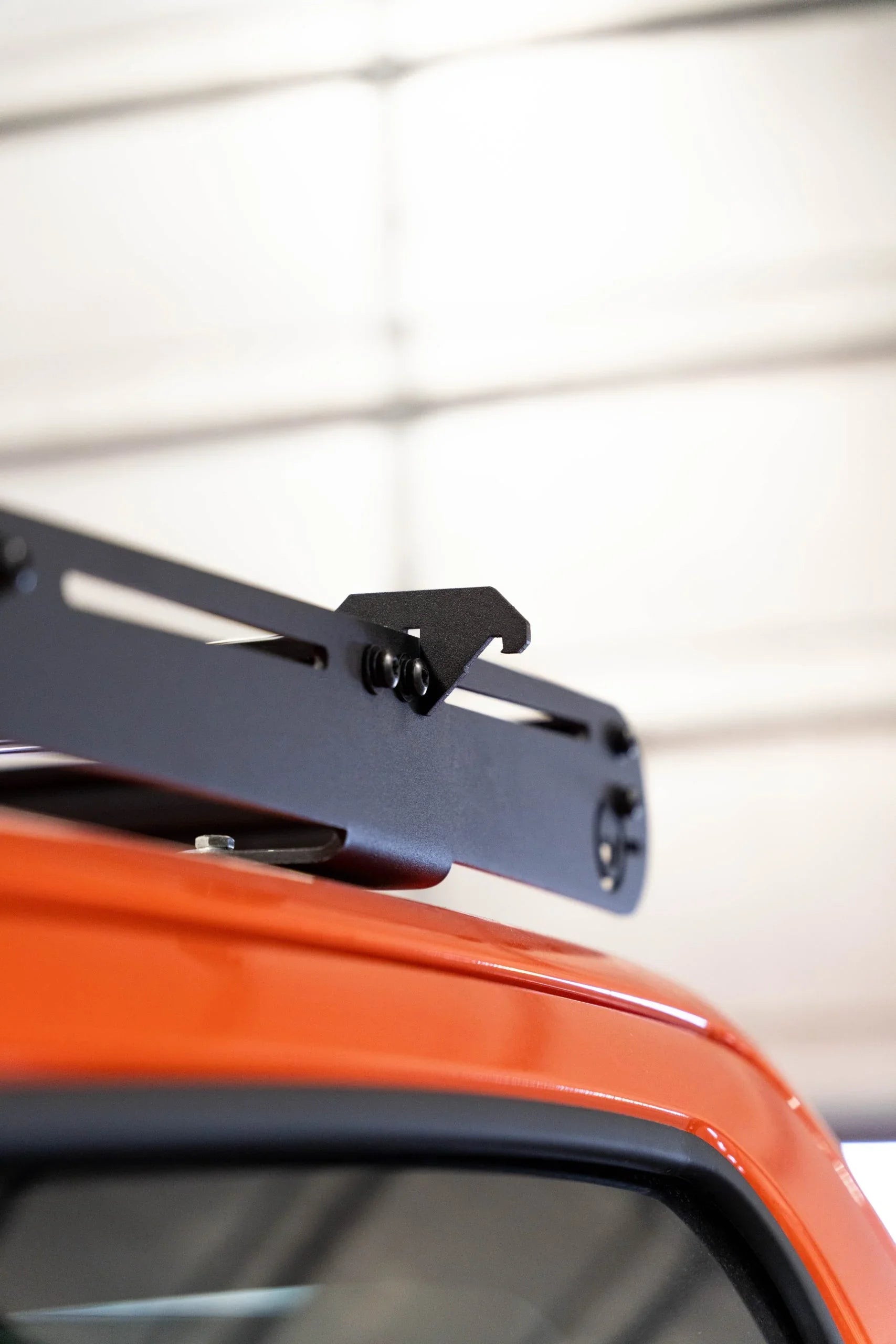 Close-up of black roof rack mount installed on orange off-road vehicle