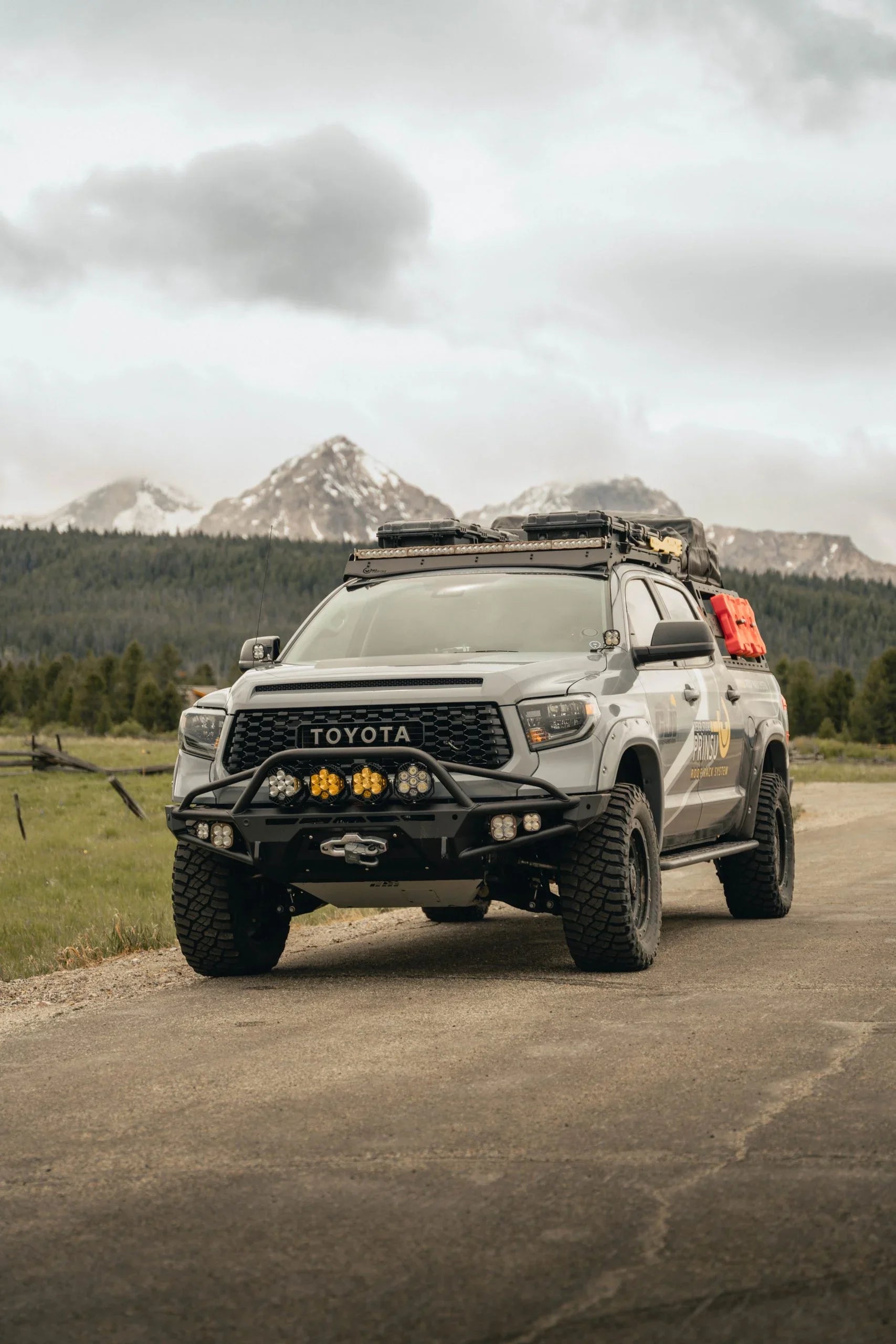 Lifted Toyota Tundra overland truck with off-road gear on mountain road, adventure-ready