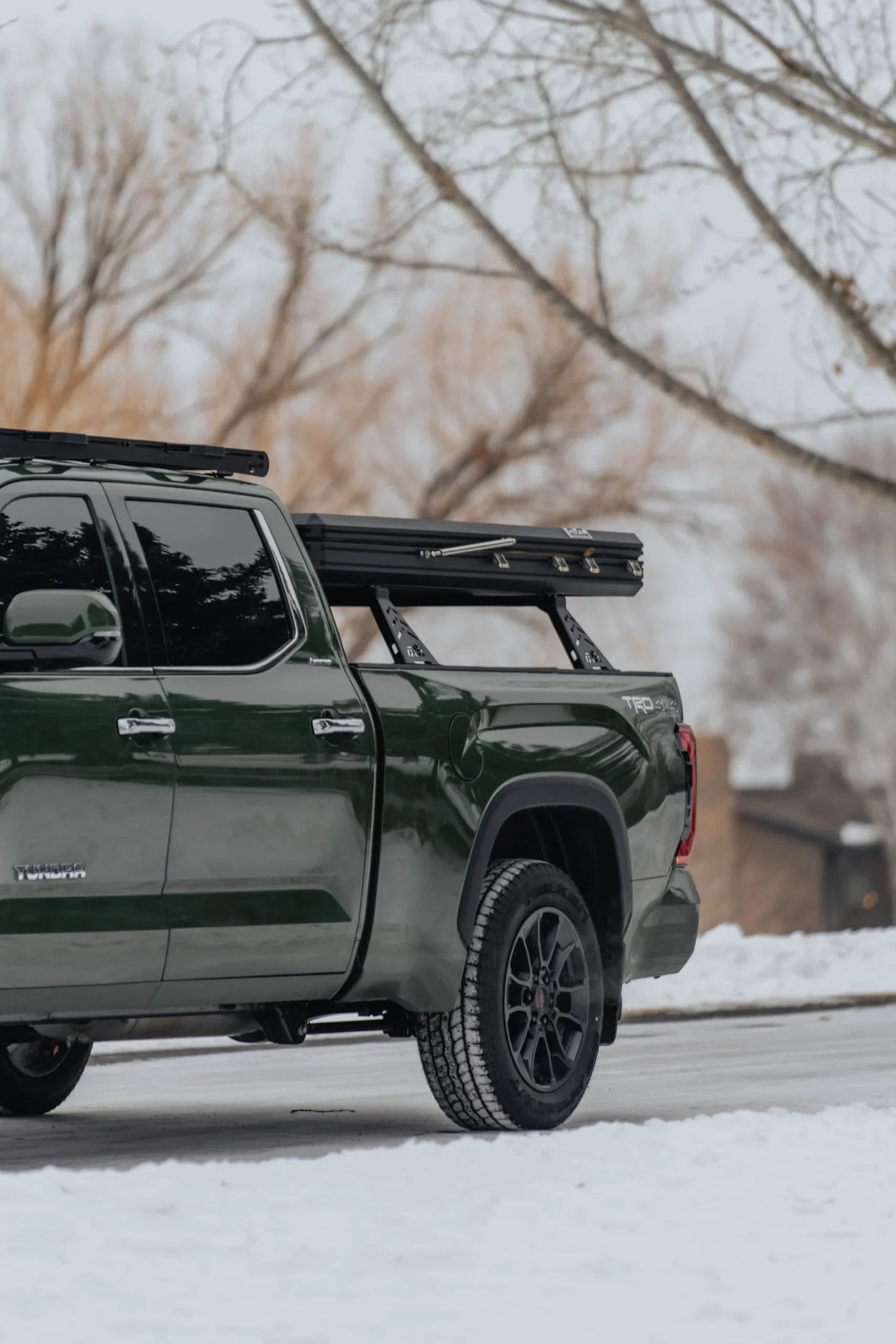 Toyota Tundra TRD pickup with overland rack and rooftop tent in snowy outdoor setting