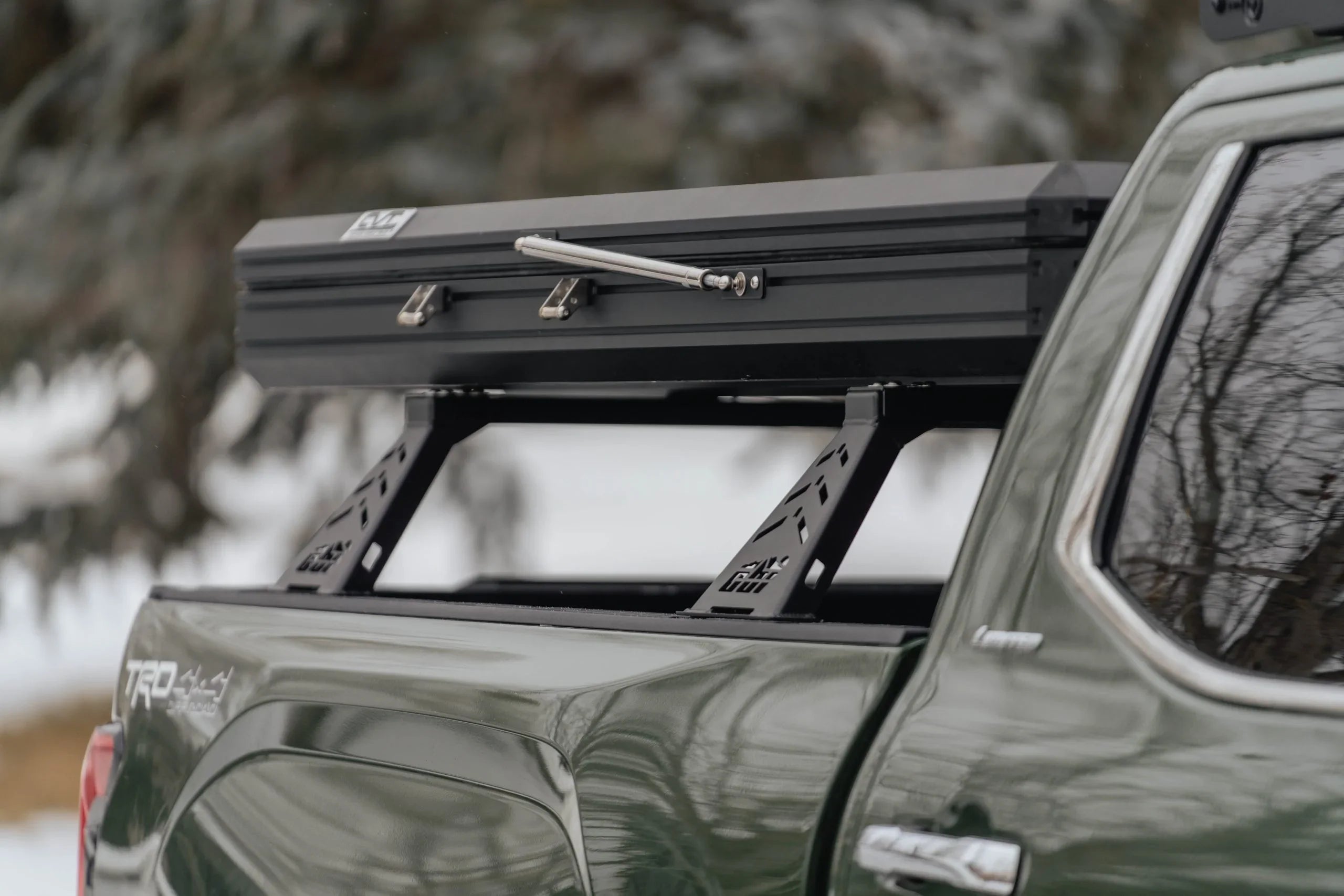 Overland bed rack with rooftop tent mounted on Toyota Tacoma in winter outdoor setting
