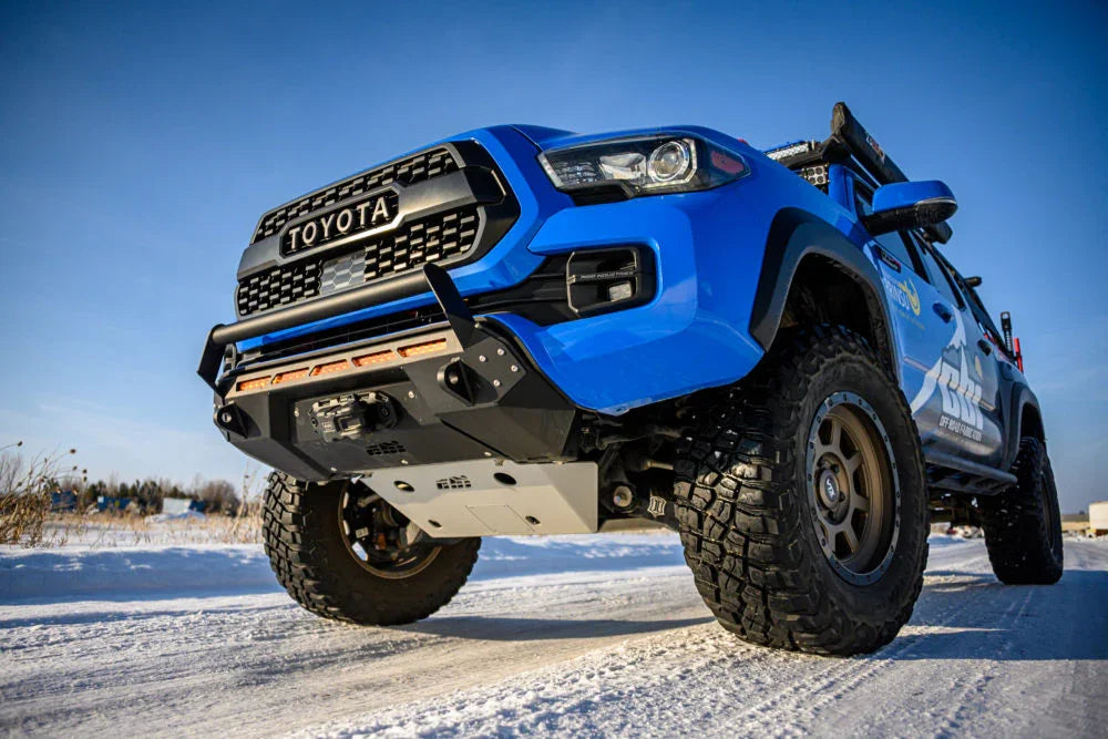 Blue Toyota Tacoma with off-road bumper and all-terrain tires on snowy outdoor trail