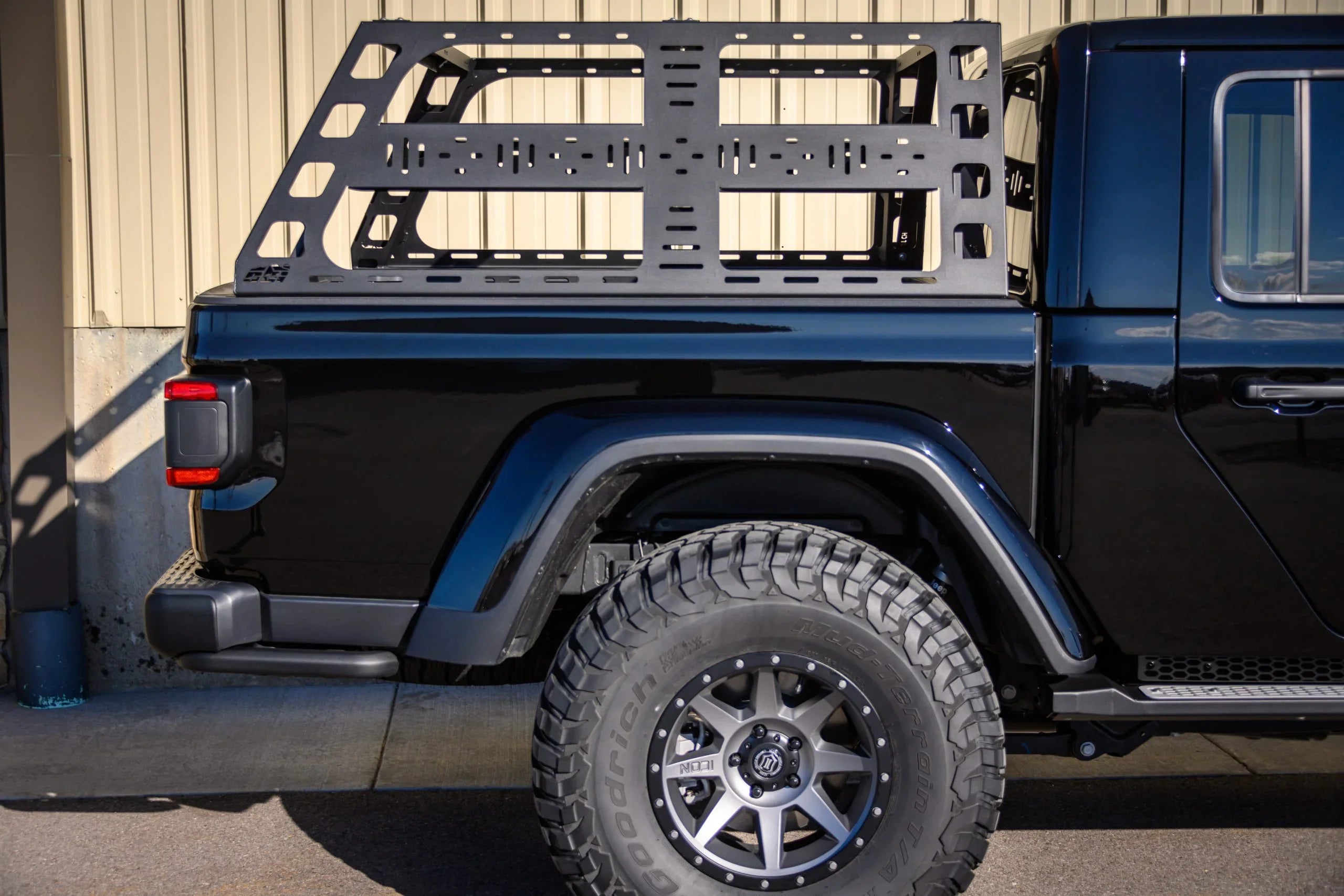 Black Jeep Gladiator with off-road tire and modular overland bed rack for expedition gear