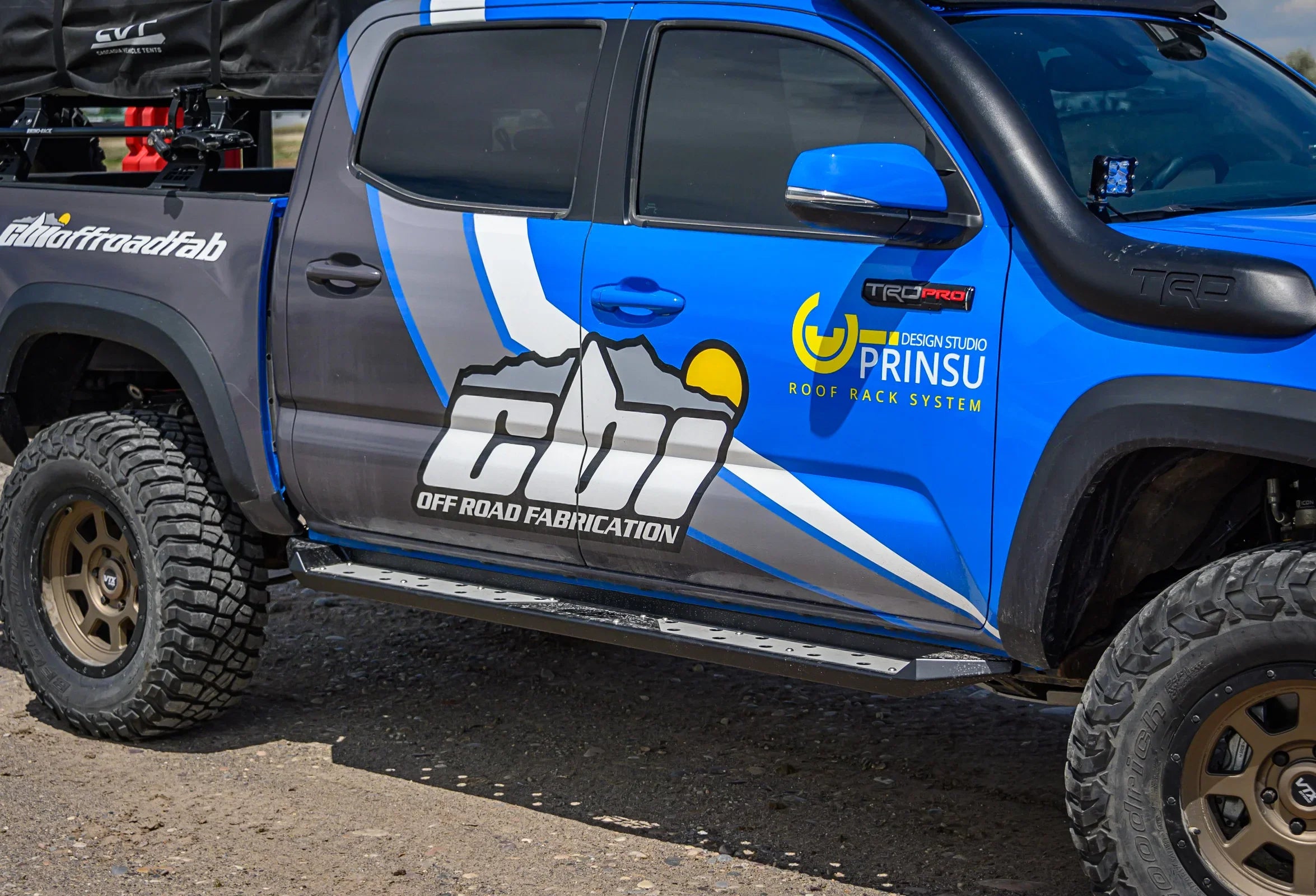 Blue off-road Toyota Tacoma with CBI Off Road Fabrication graphics and rugged accessories