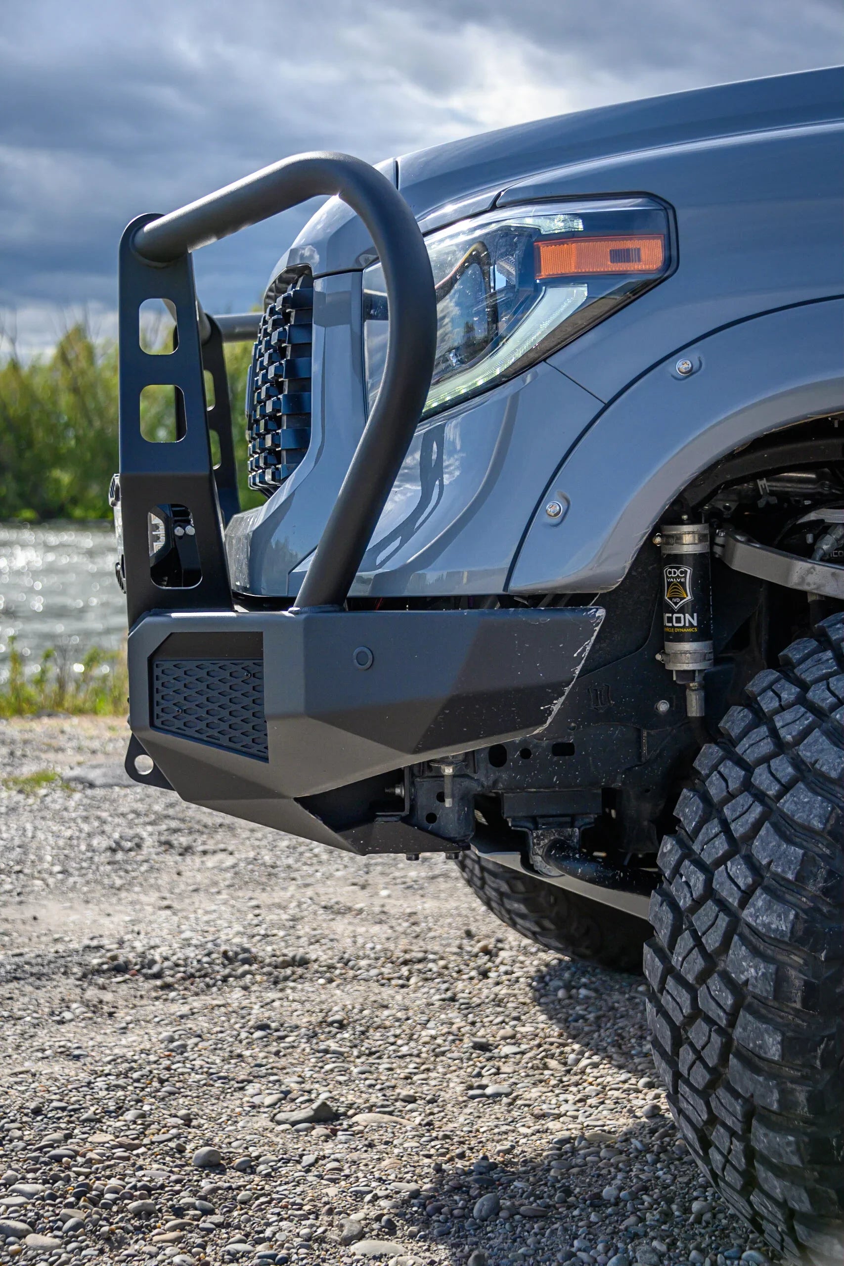Off-road truck with heavy-duty front bumper and rugged tires on gravel, outdoor setting