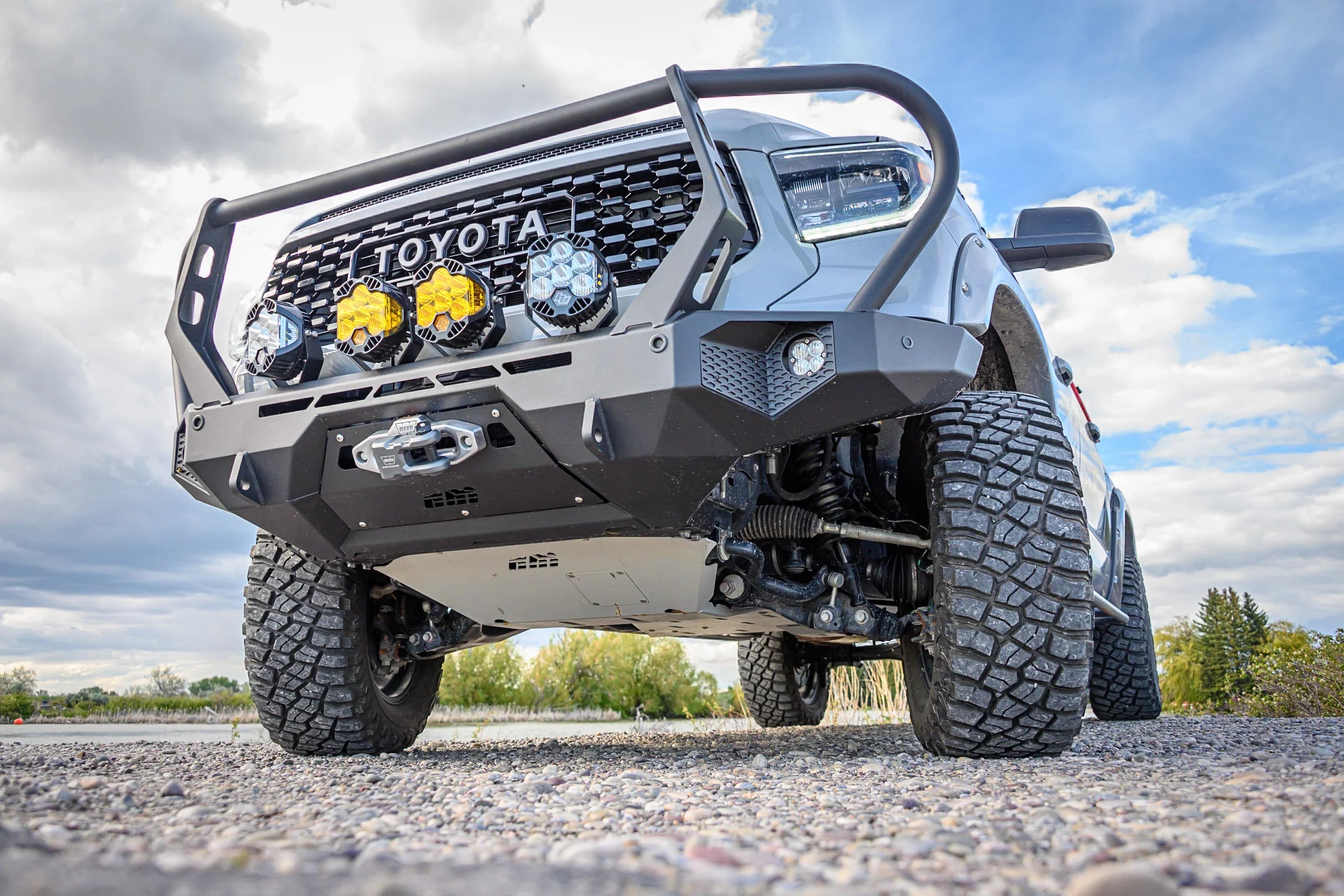 Toyota truck with off-road bumper, skid plate, and LED lights on rugged all-terrain tires