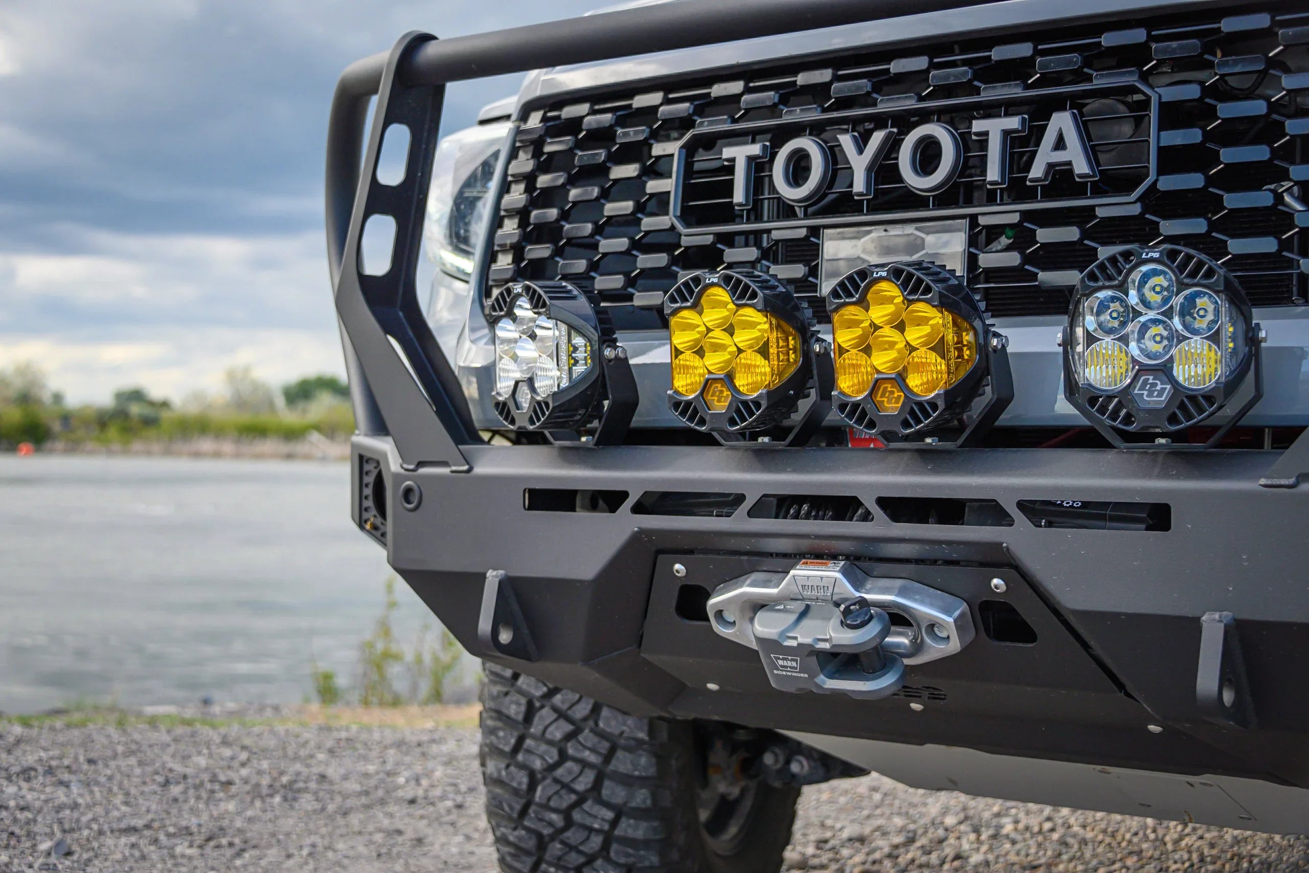Toyota truck front bumper with off-road LED lights, winch, and rugged grille outdoors