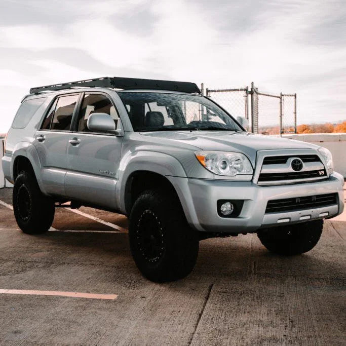 Silver Toyota 4Runner SUV with roof rack, off-road tires, in outdoor parking lot