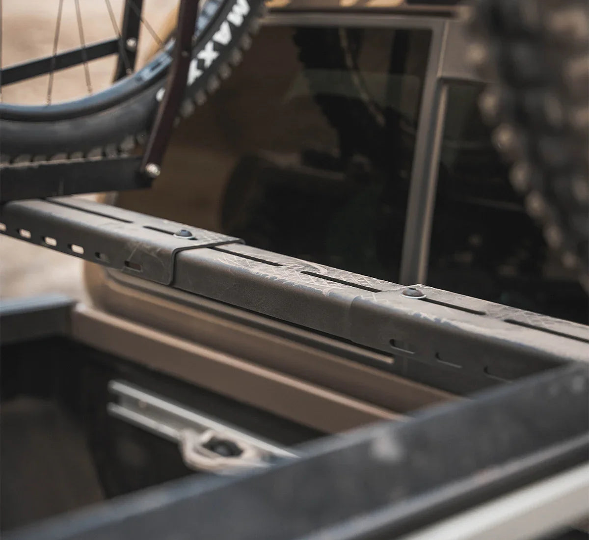 Expandable crossbar mounted on vehicle bed with bike rack and off-road accessories