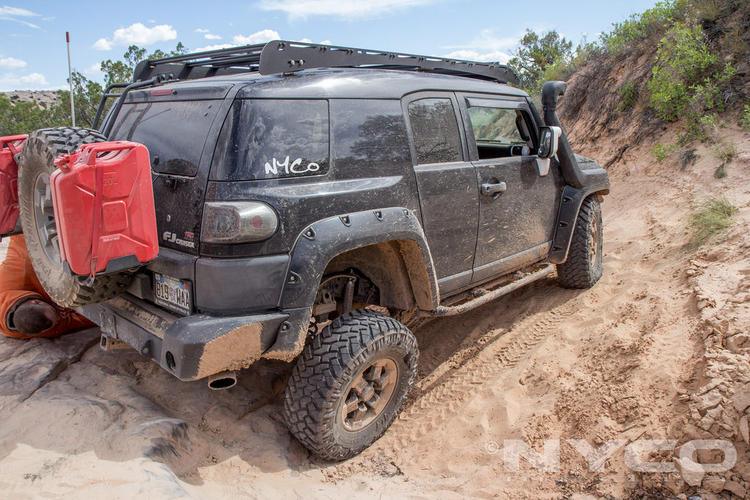 Toyota FJ Cruiser with roof rack and spare fuel can off-roading on a dirt trail