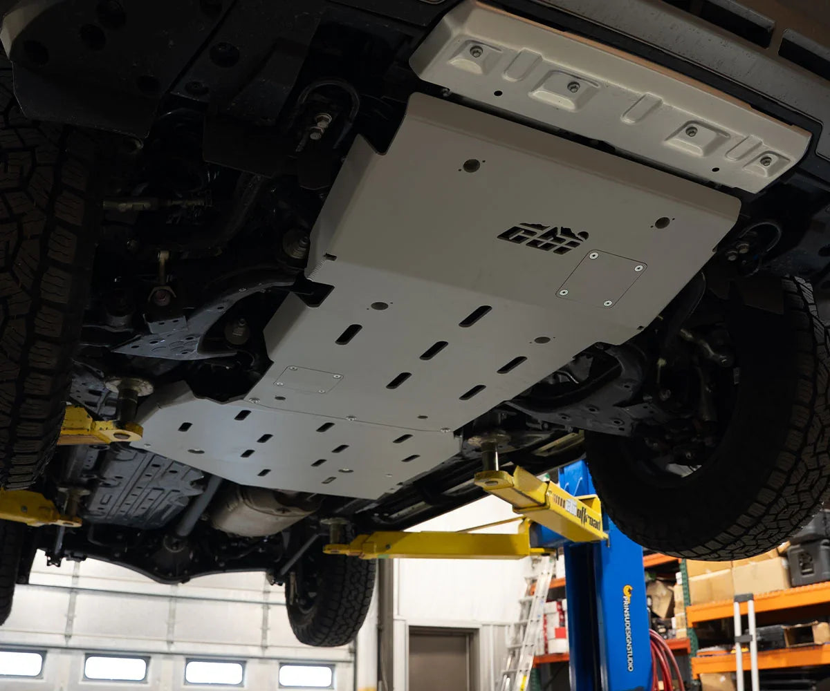 Aluminum skid plates installed under a lifted off-road vehicle in a garage