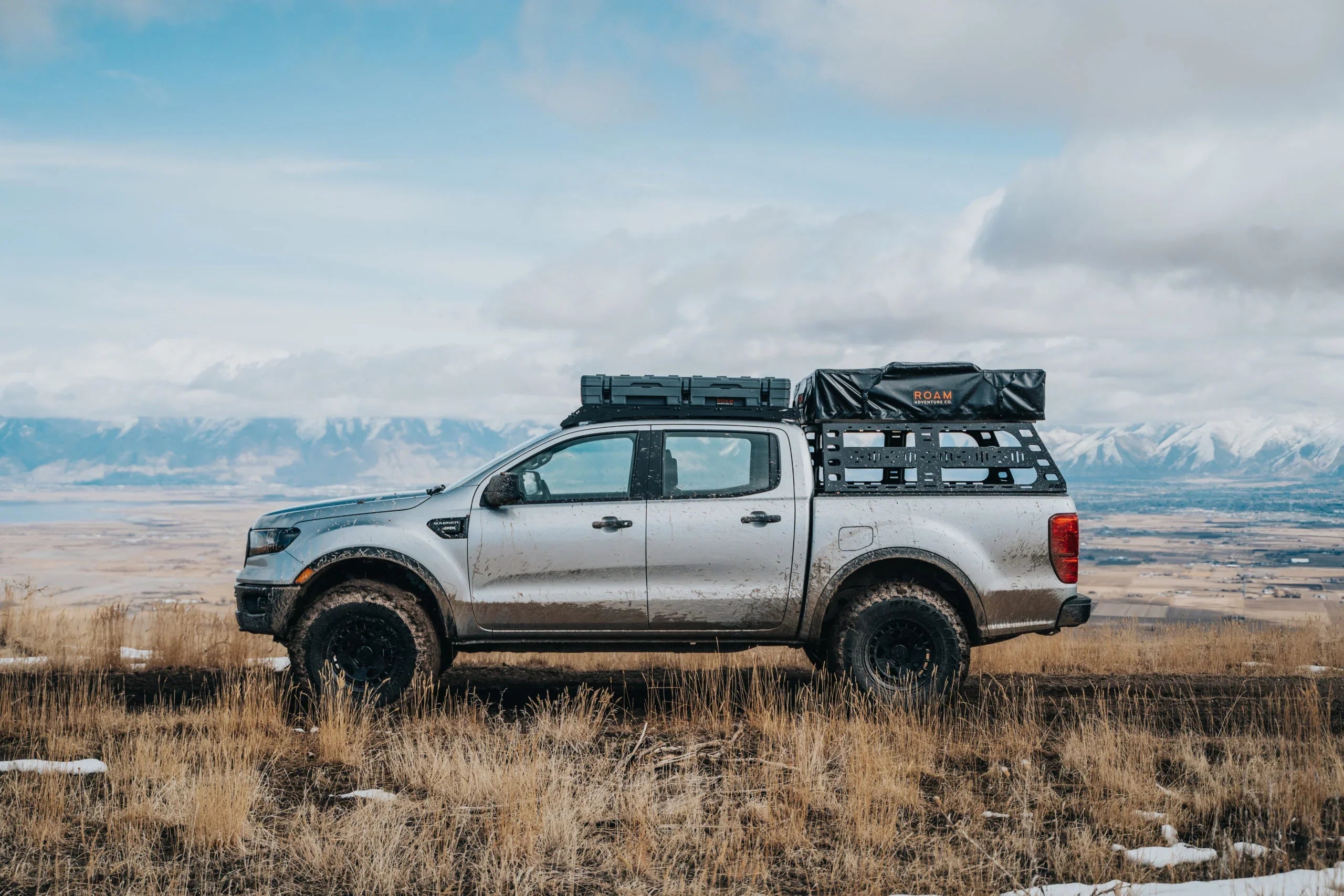Ford Ranger with cab height bed rack and rooftop storage, off-road in scenic mountain terrain