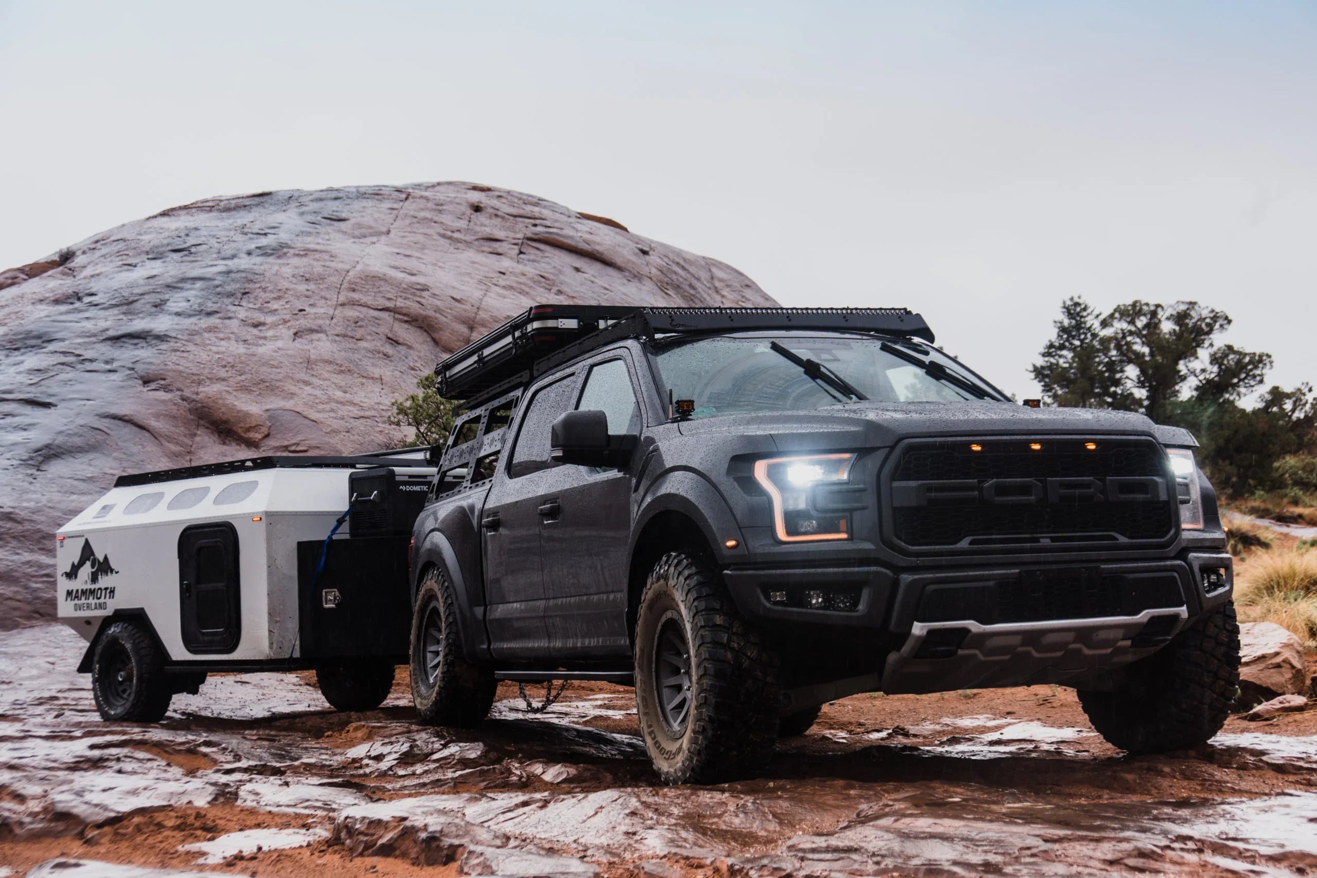 Ford Raptor with roof rack towing Mammoth Overland trailer on rocky terrain