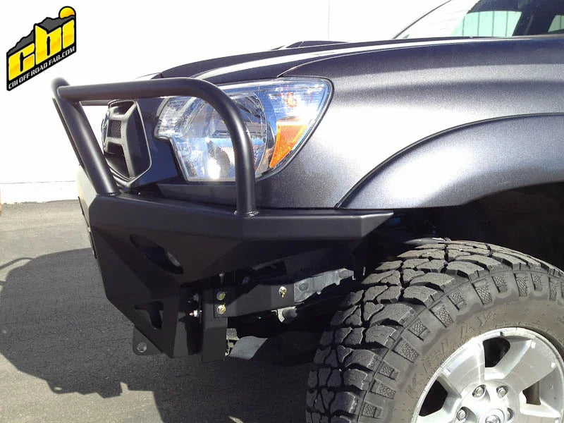 Front off-road steel bumper installed on Toyota Tacoma with rugged tires, sunlight