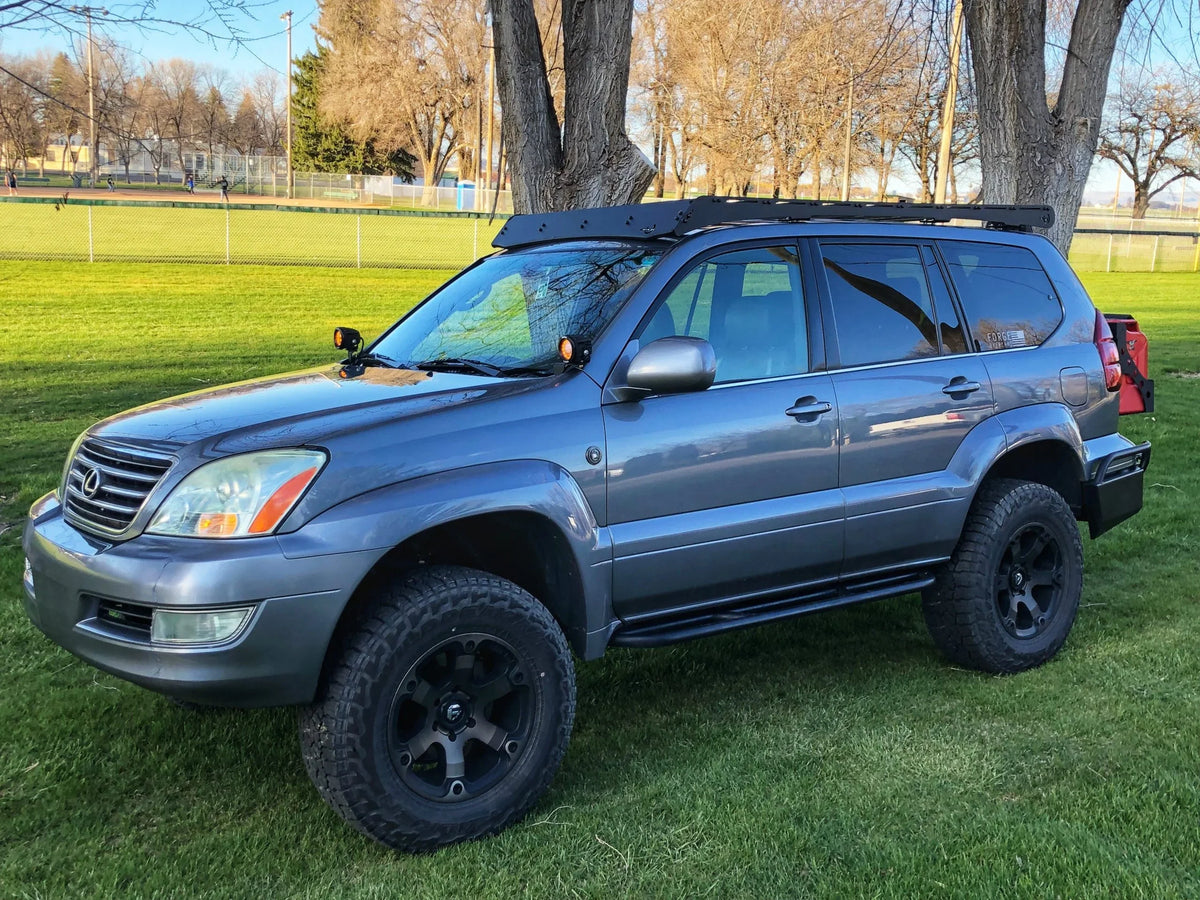 Lifted Lexus GX470 with Prinsu roof rack and off-road accessories in a grassy park.