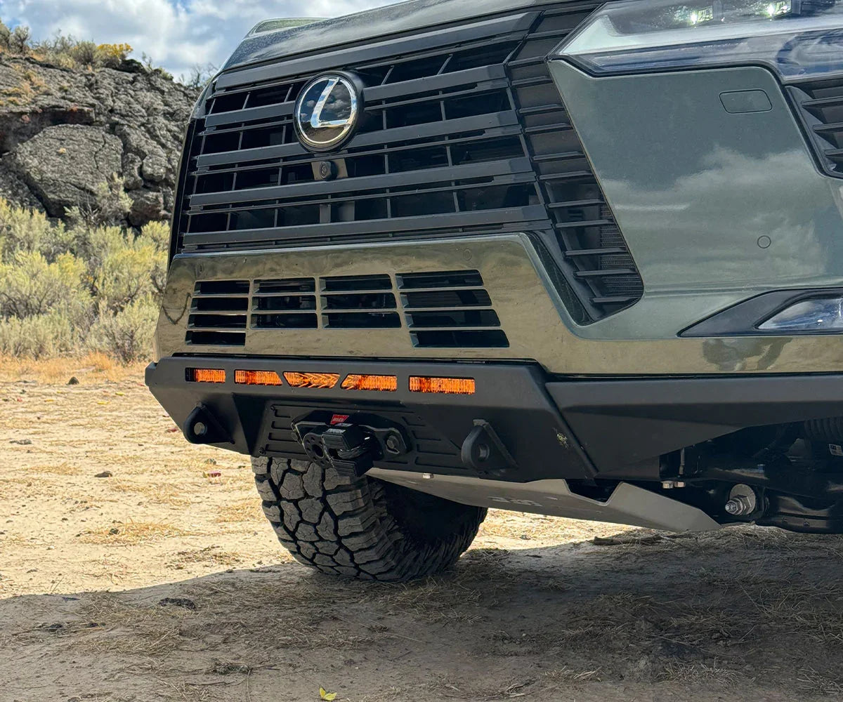 Lexus SUV with rugged off-road front bumper and amber lights on dirt trail
