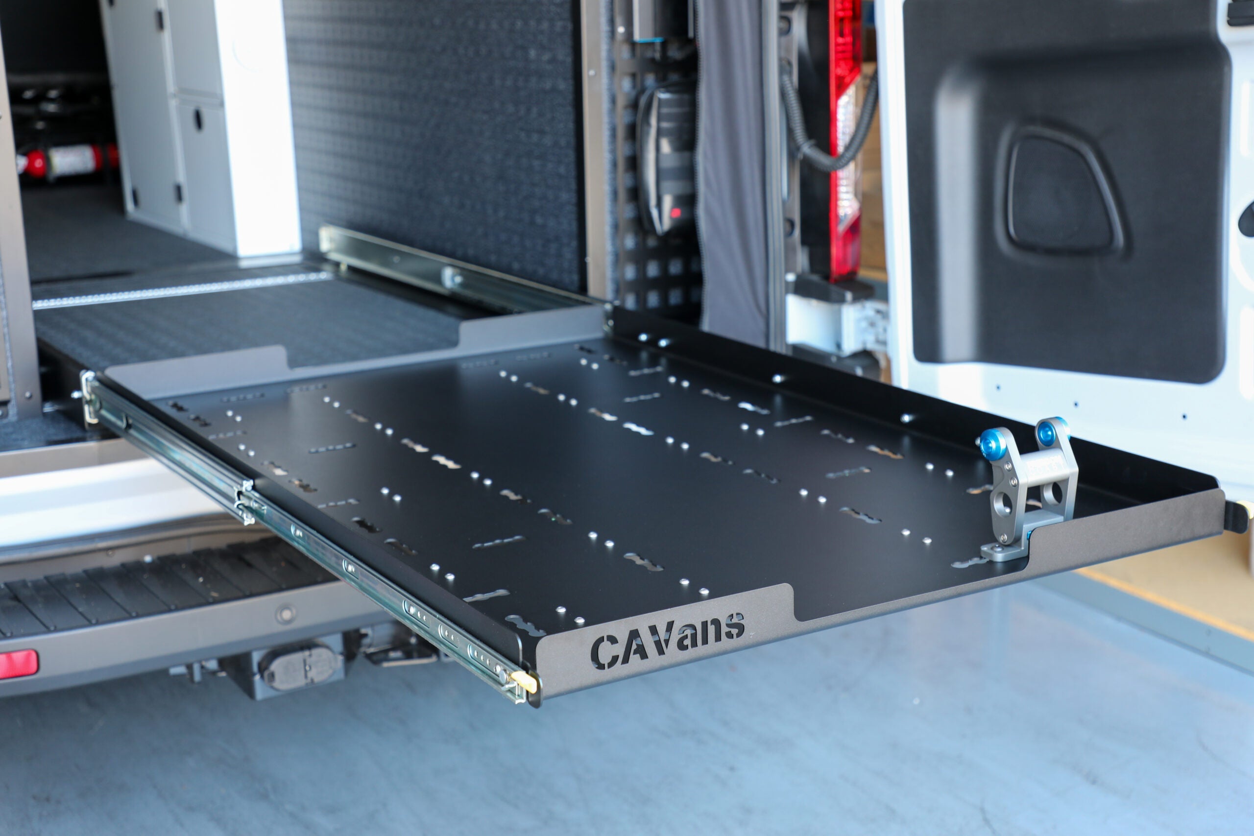 Metal slide-out deck installed in a van cargo area for overlanding vehicle storage