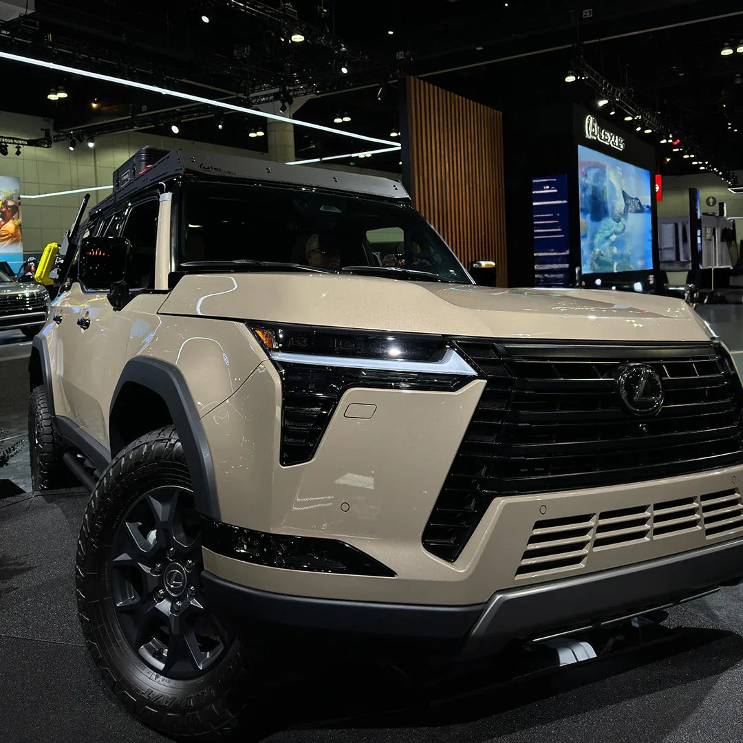Beige Lexus GX 550 overland SUV with rugged tires displayed at auto show