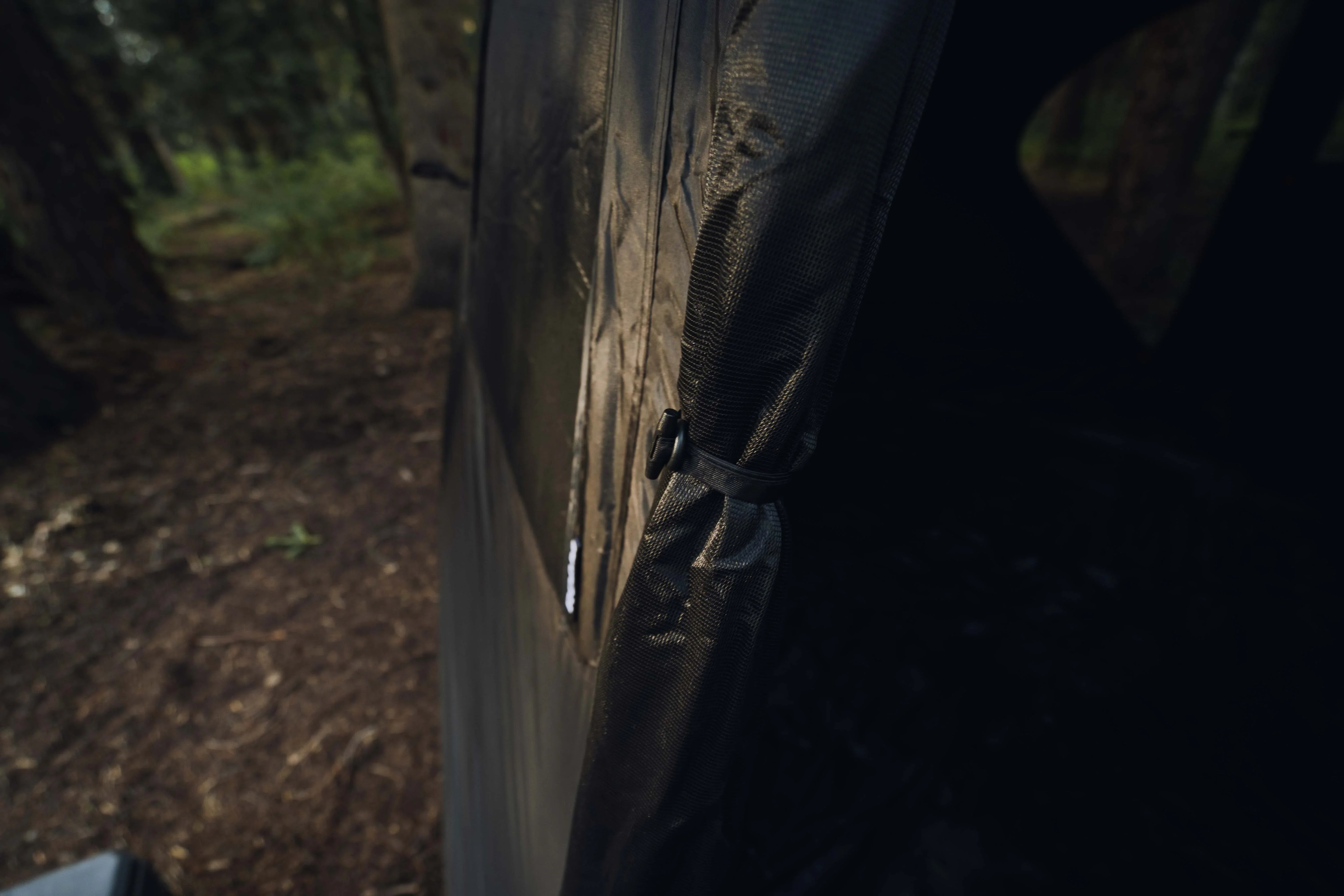 close-up of outdoor expedition camping tent door with tie in forest setting