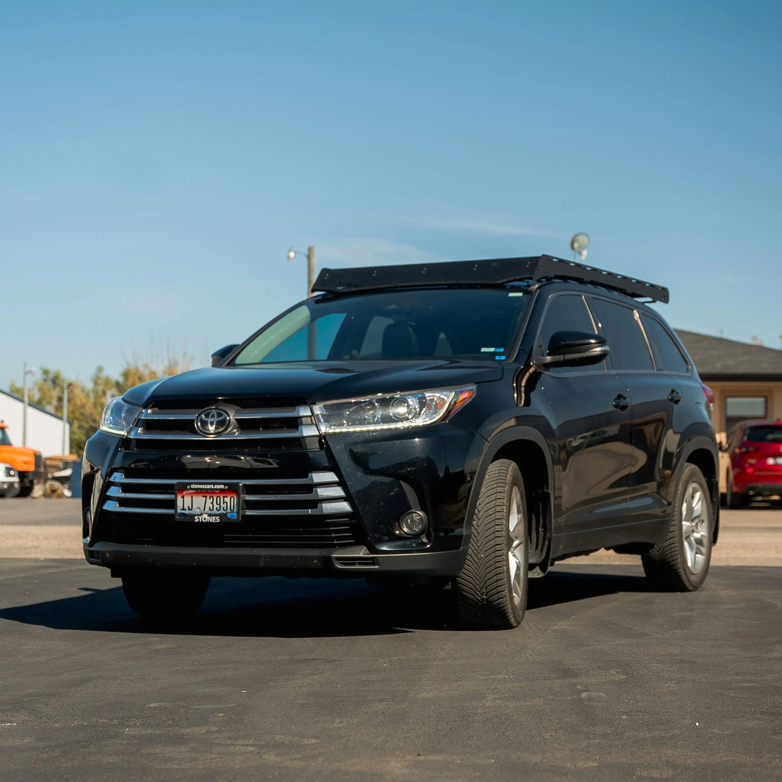 Black Toyota Highlander SUV with roof rack for overlanding parked outdoors