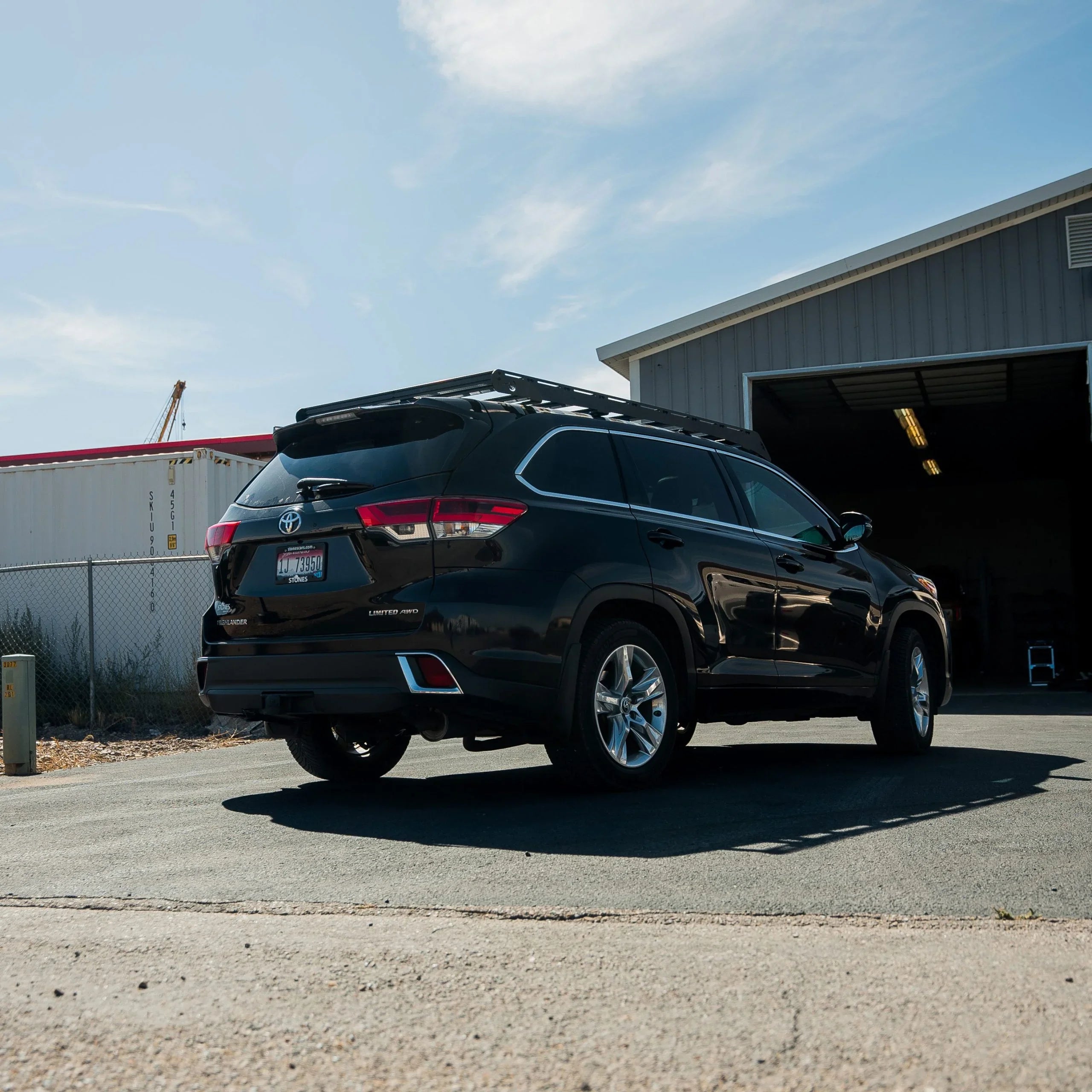 Black Toyota Highlander Limited AWD with roof rack in front of a garage outdoors