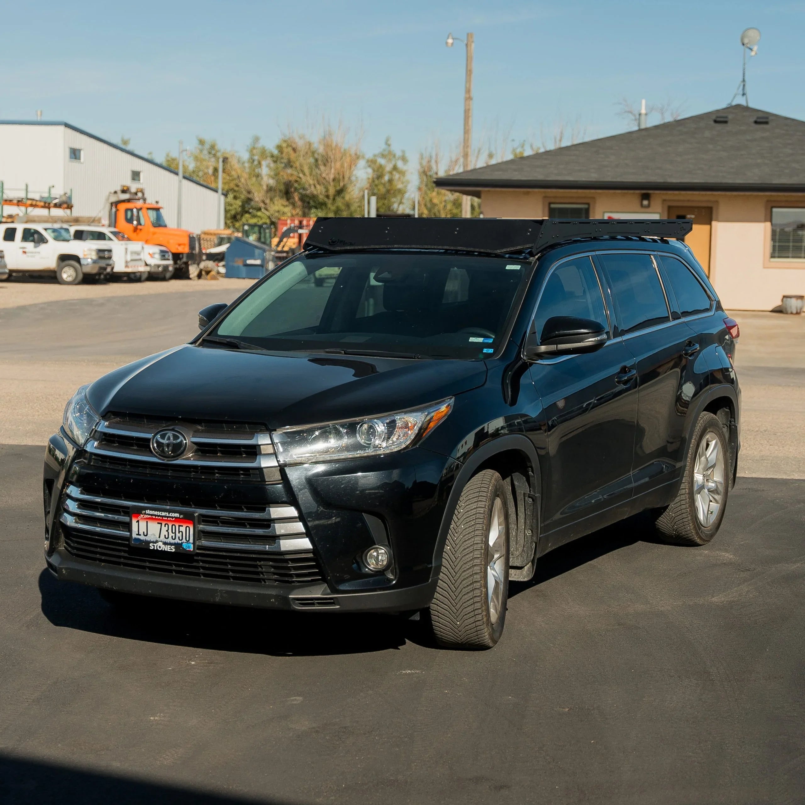 Black Toyota Highlander SUV with roof rack parked outdoors, ideal for overlanding accessories