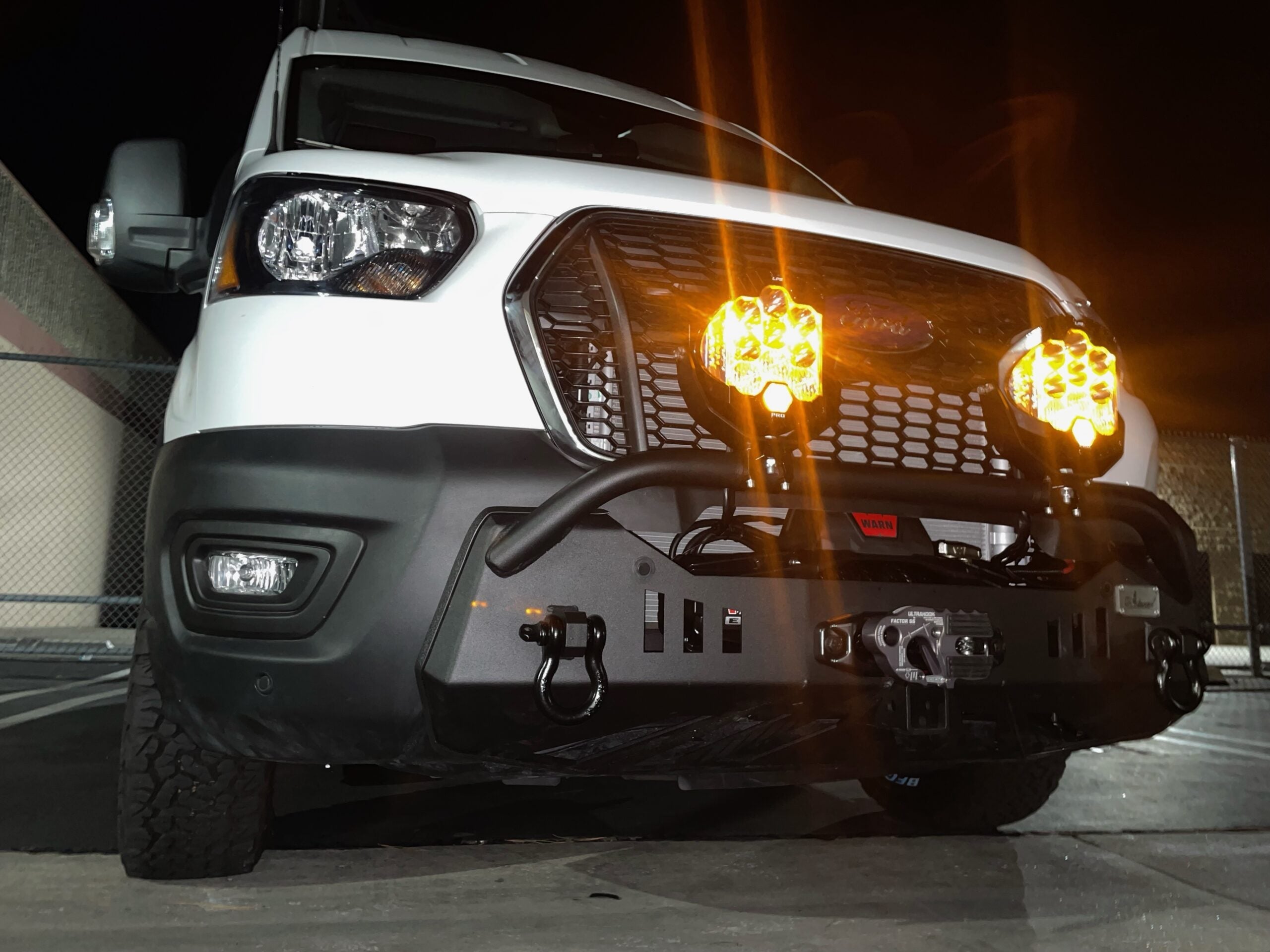 Front view of off-road van with aftermarket bumper and amber LED driving lights at night