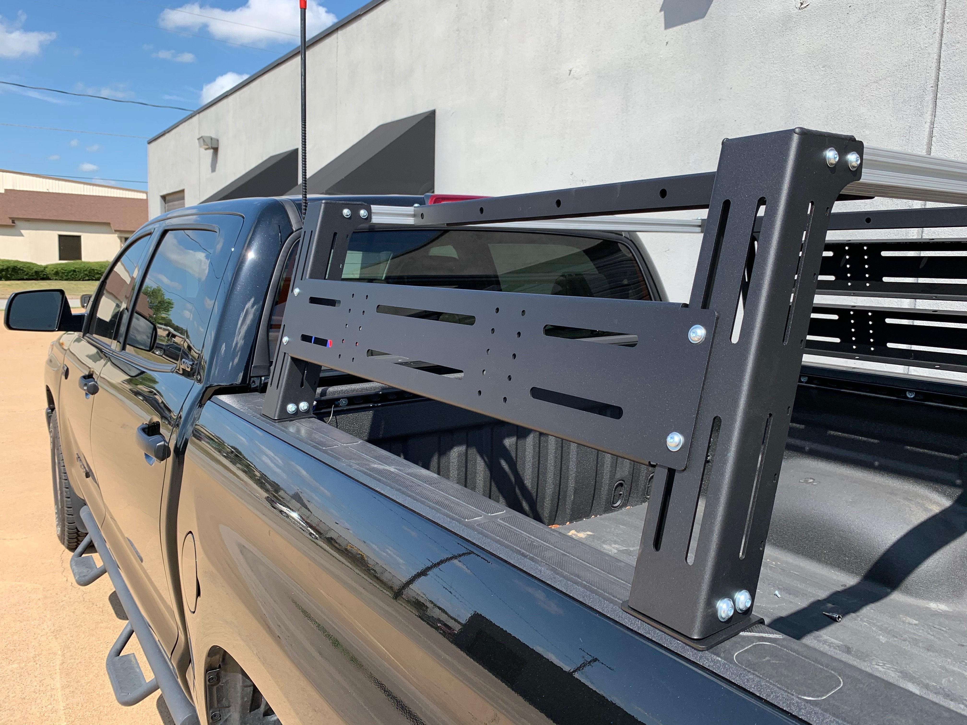 Black pickup truck with modular bed rack for overlanding and off-road gear shown outdoors