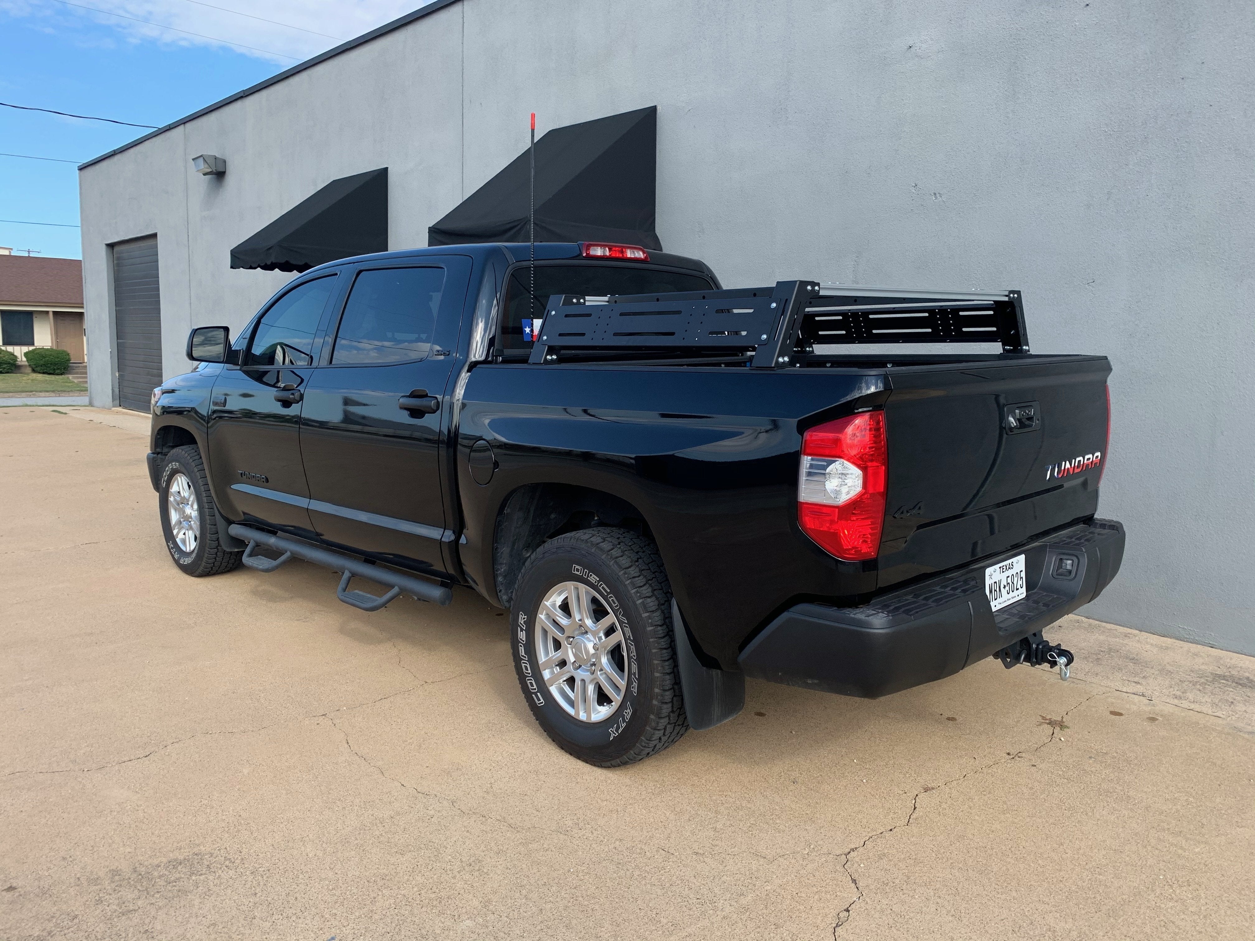 Black Toyota Tundra with overlanding bed rack parked by a building, outfitted for adventure camping.